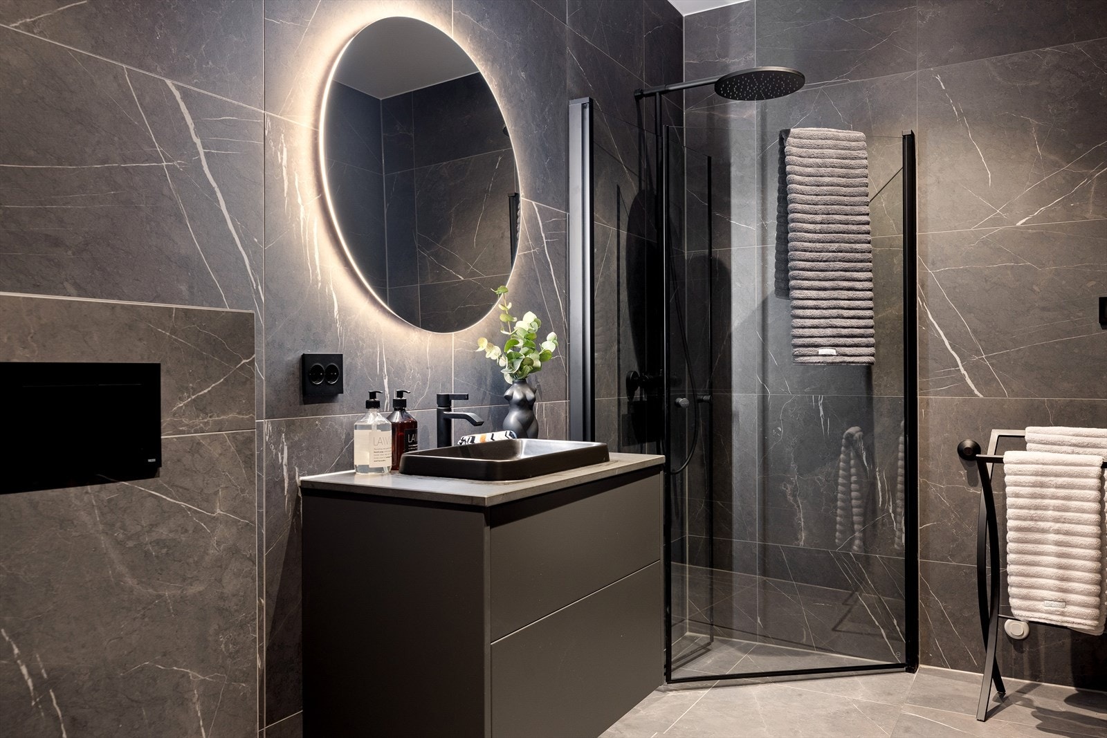 Badet er lekkert flislagt og innredet med dusjhjørne, servant med skuffeseksjon og speil med integrert belysning. Det er også montert opplegg for vaskemaskin. Galleribilde