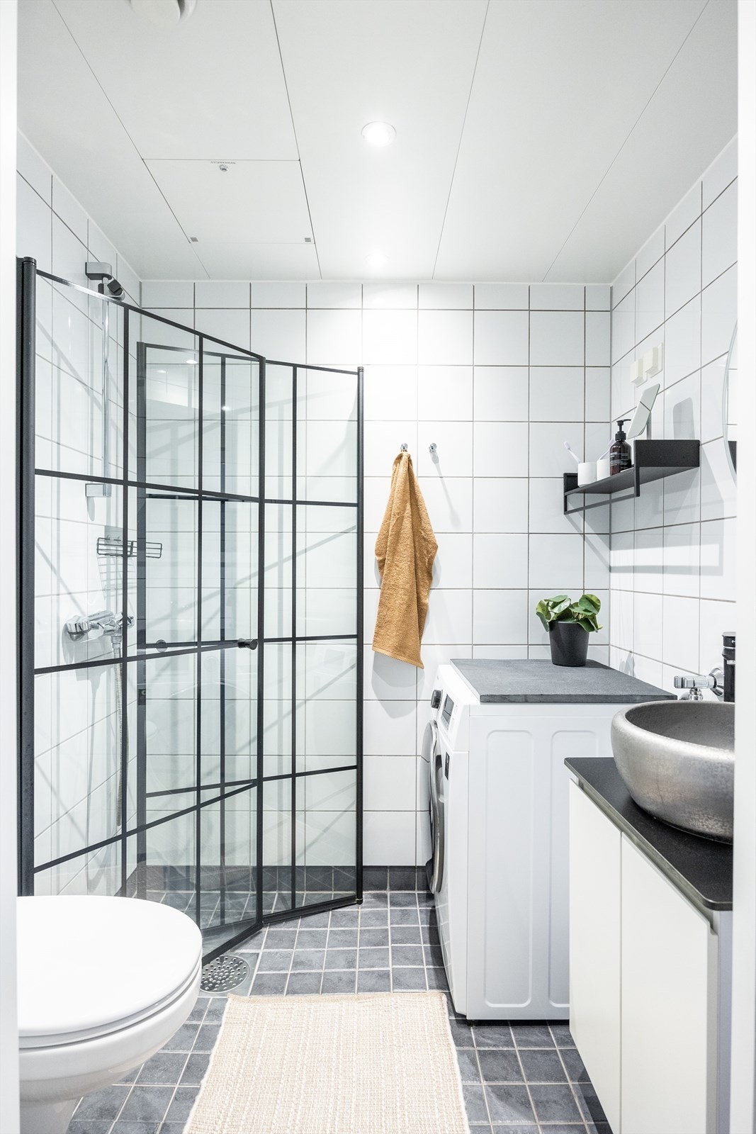 Flislagt bad med downlights i himling og varme i gulv. Videre er badet utstyrt med veggmontert wc, dusjhjørne med innfellbare dusjdører, servantskap og opplegg for vaskemaskin. Galleribilde