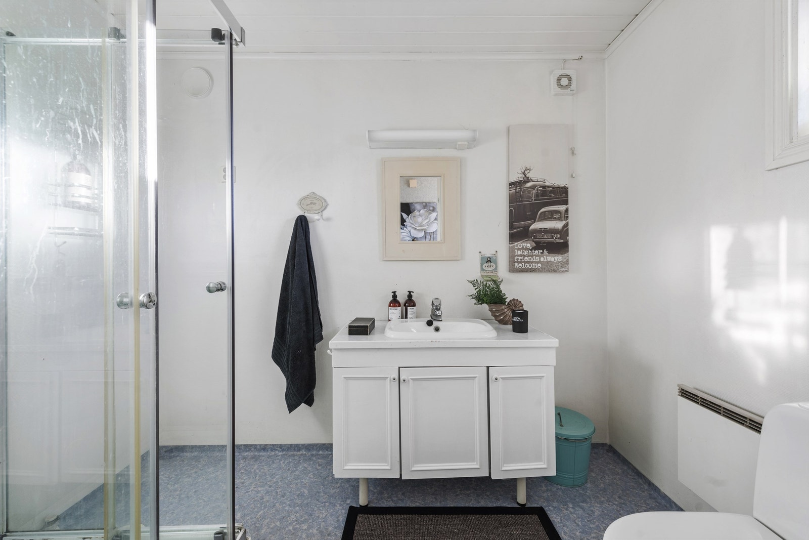 Bad i 1. etasje med toalett, dusjkabinett og innredning i hvit utførelse. Vegghengt panelovn Galleribilde