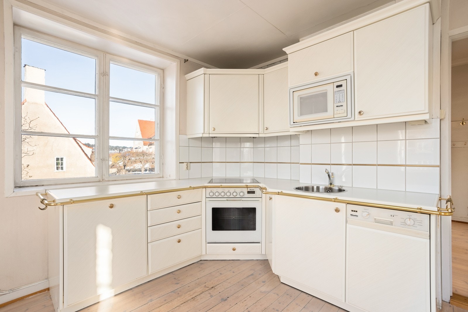 Eldre kjøkkeninnredning fra Miele med profilerte fronter, laminat benkeplate, fliser over benk og nedfelt kum. Galleribilde