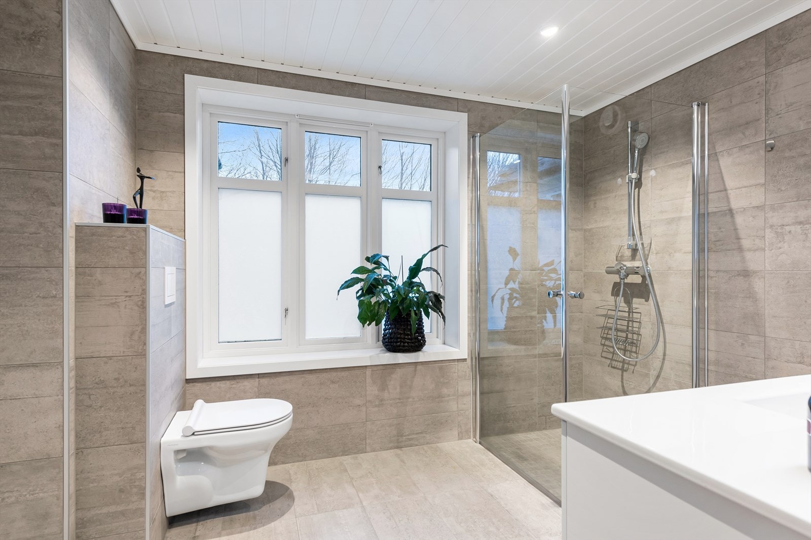 Badet fremstår i dag som både lekkert og tidsriktig med flislagte gulv/vegger og malt panel i taket med innfelte spotter. Galleribilde