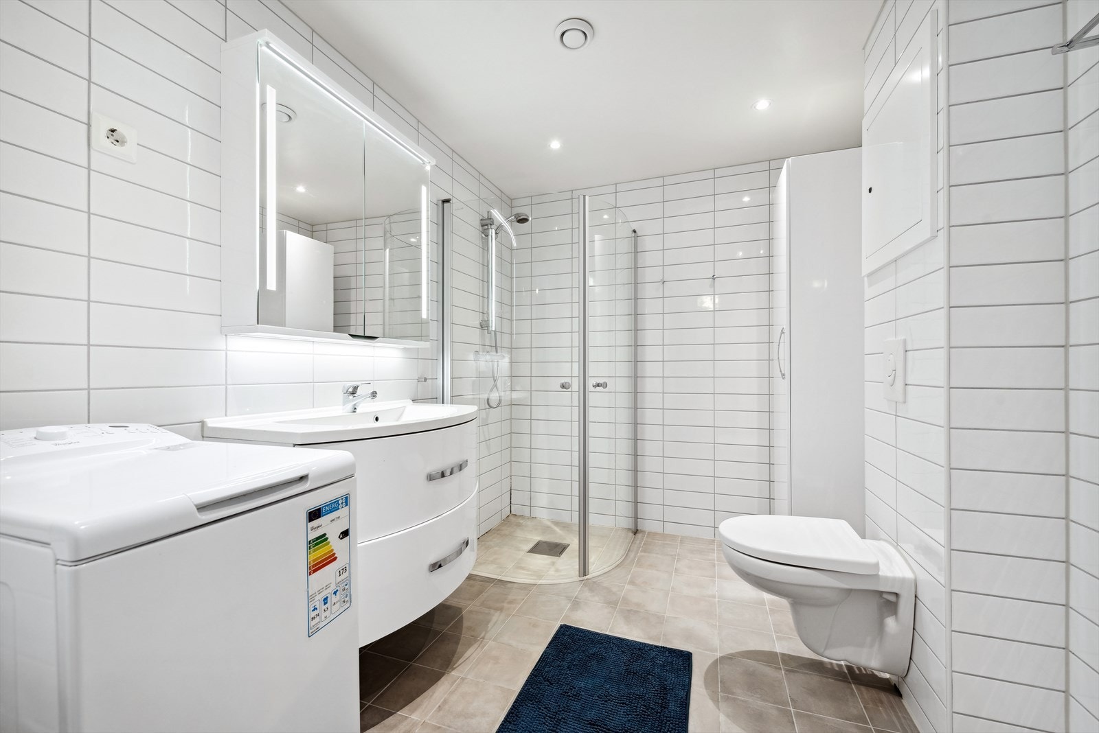 Det romslige badet har downlights i tak, keramiske fliser på vegg og gulv, samt både gulvvarme og opplegg for vaskemaskin. Galleribilde