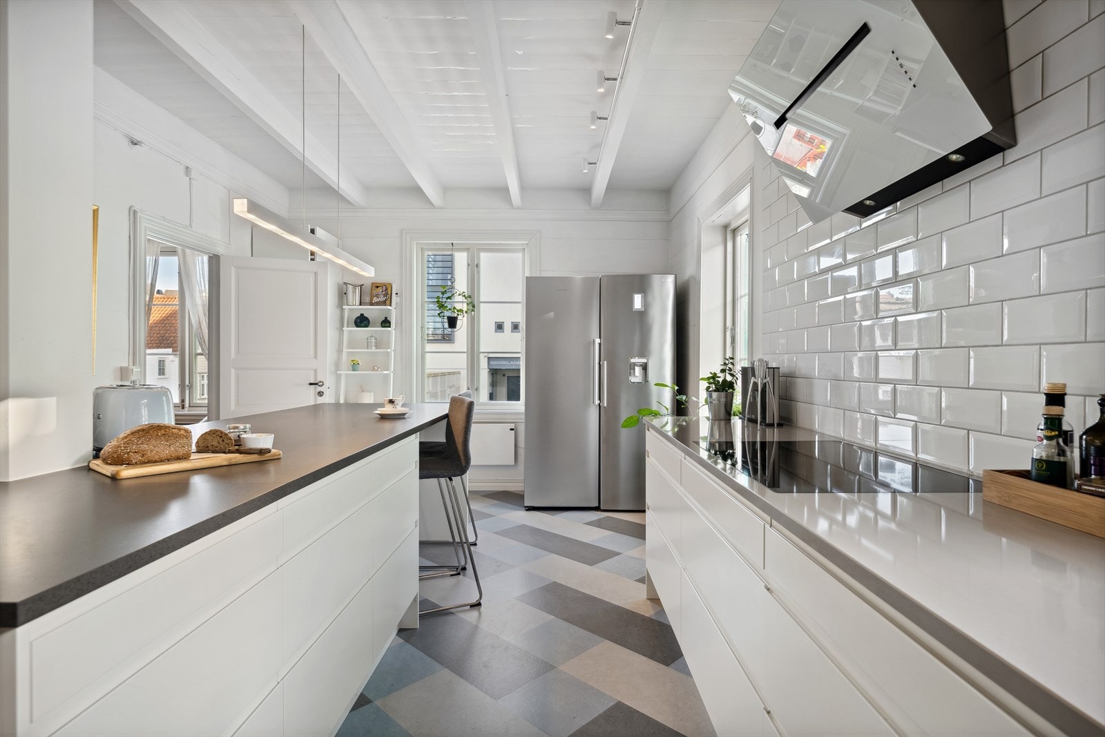 Kjøkkeninnredningen er i moderne stil med glatte, hvite fronter med benkeplate i stein. Galleribilde