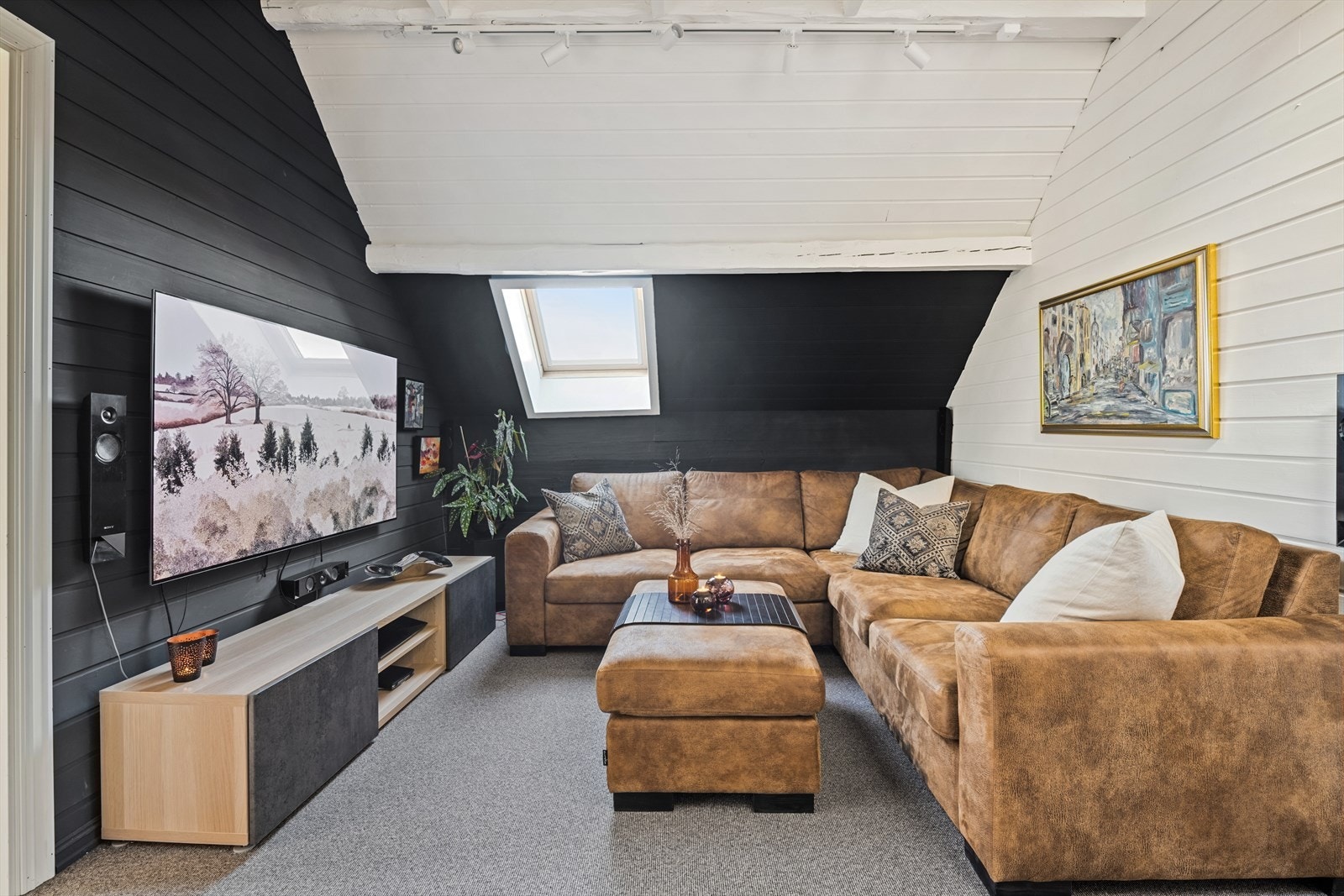 Loftstue som er innredet som TV stue. Det er lagt teppe av teppelegger på flere rom på loft. Galleribilde