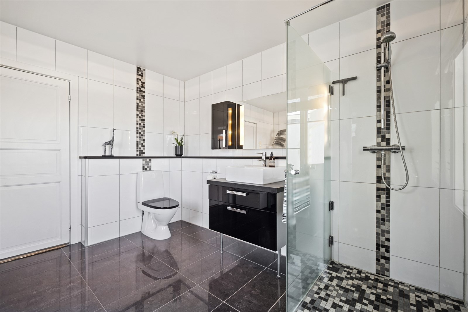 Badet har toalett, en dusjnisje bak vegg i frostet glass, og opplegg for vaskemaskin. Det er i 2019 montert inn et høyskap på badet. Galleribilde