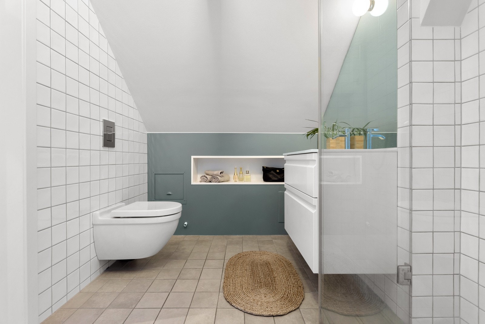 Badet er fra 2012, og ble oppgradert med innredning med nedfelt servant med skuffer under i 2021. Videre er det veggmontert toalett og innadslående dusjvegger. Galleribilde