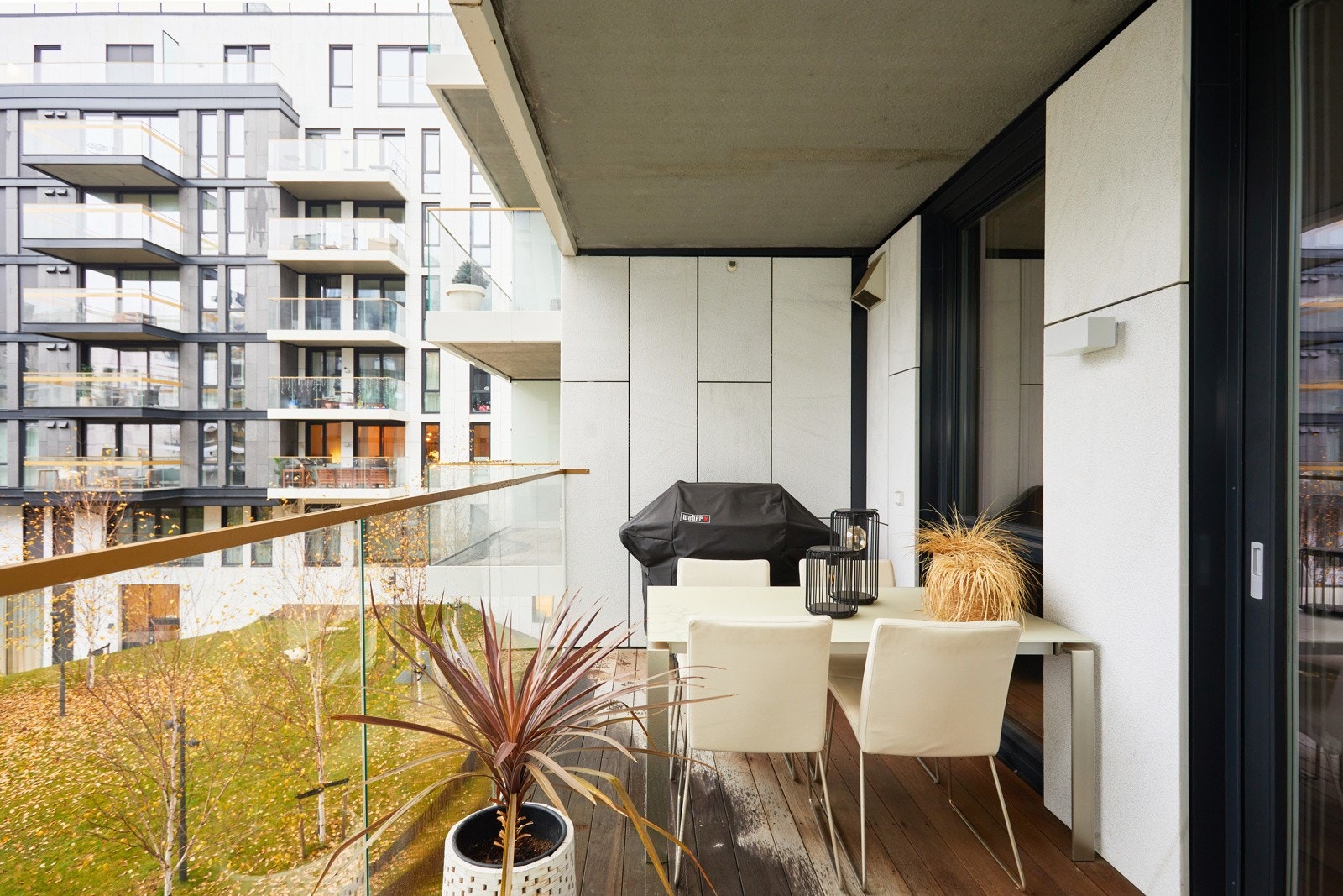 Balkongen er overbygget, har terrassebord på gulv og stilrent rekkverk med glassfelt. Det er også montert utebelysning og stikkontakt. Galleribilde