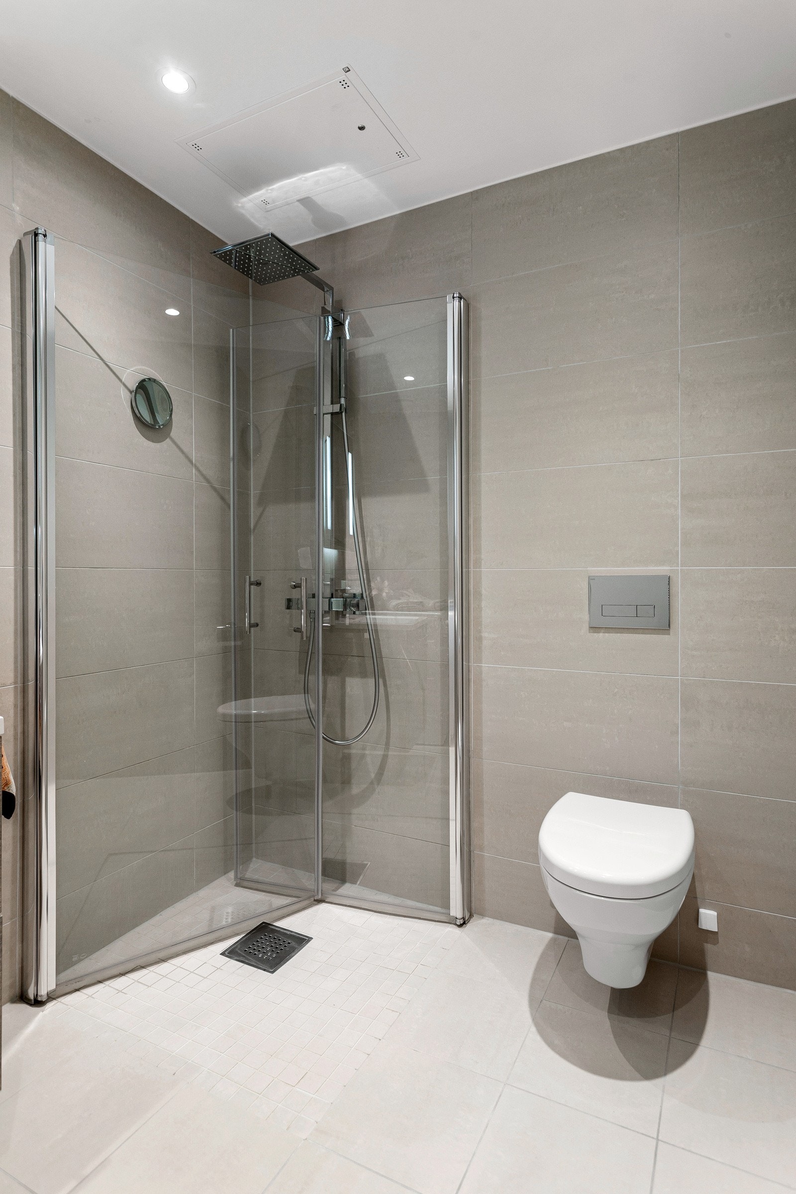 Baderommet er også utstyrt med dusjhjørne med innfellbare glassdører og både hånd- og regnfallsdusj, samt vegghengt toalett. Mekanisk avtrekk. Galleribilde