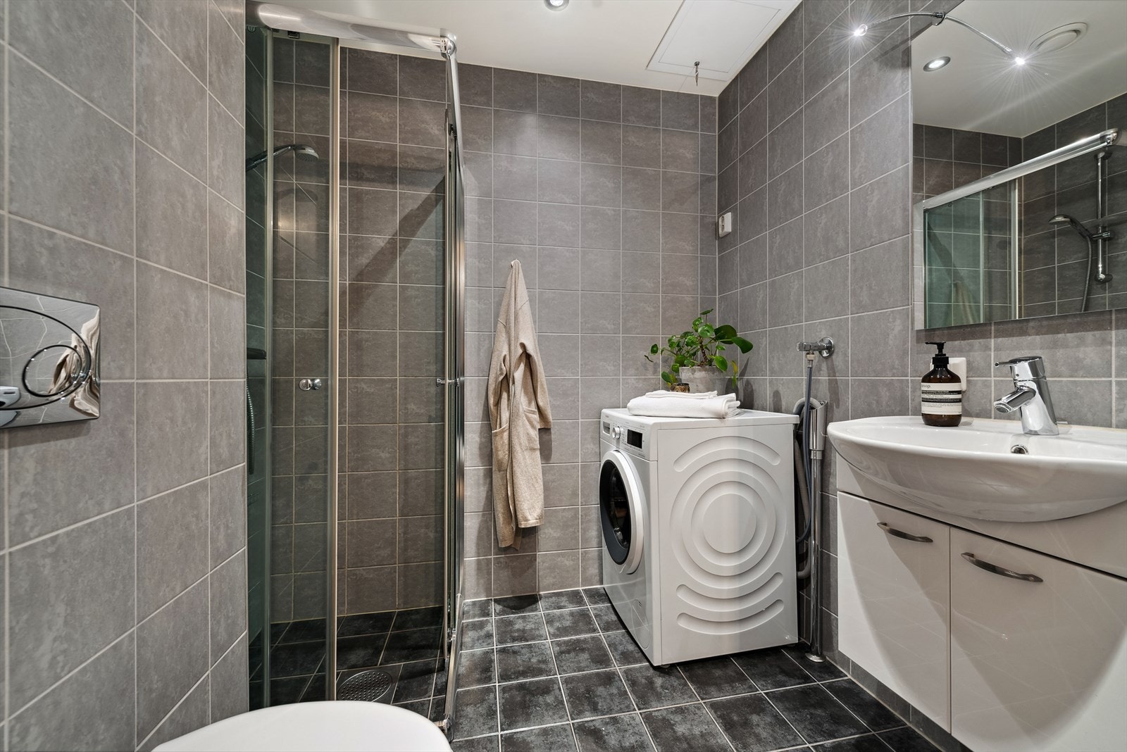 Delikat flislagt baderom med behagelig varme i gulv og opplegg/plass til vaskemaskin. Galleribilde