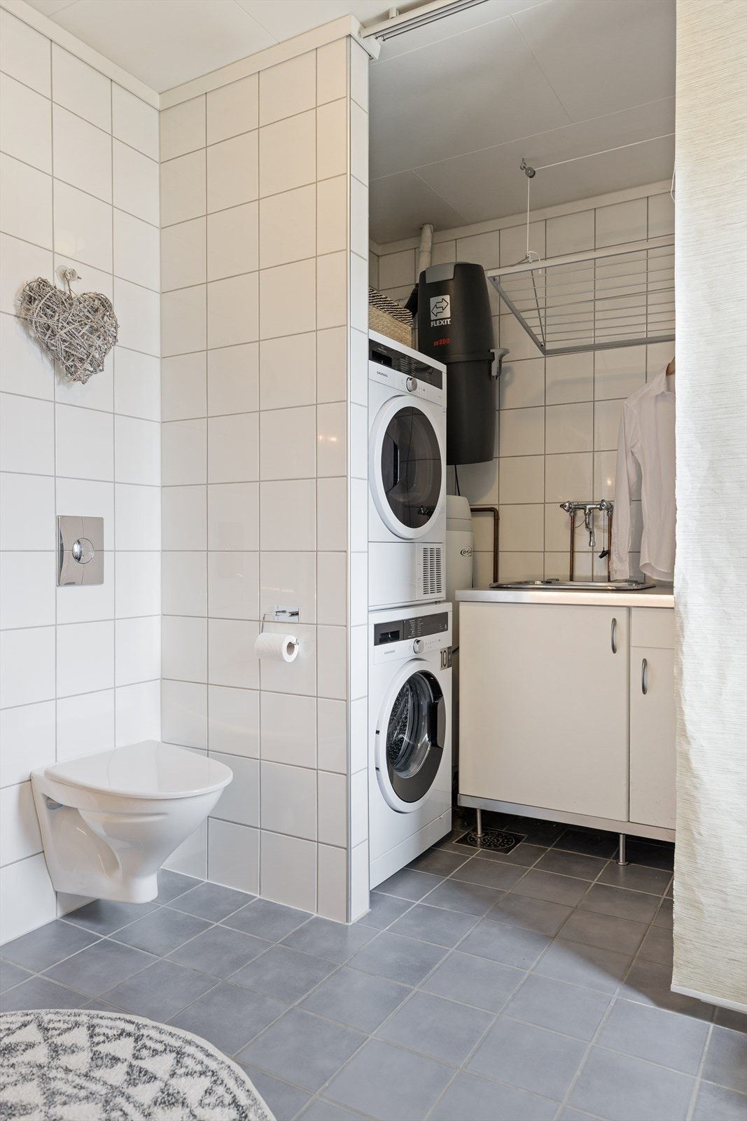 Badeinnredningen består av heldekkende servant på skuffeinnredning, veggmontert toalett, dusjhjørne og opplegg for vaskesøyle. Galleribilde