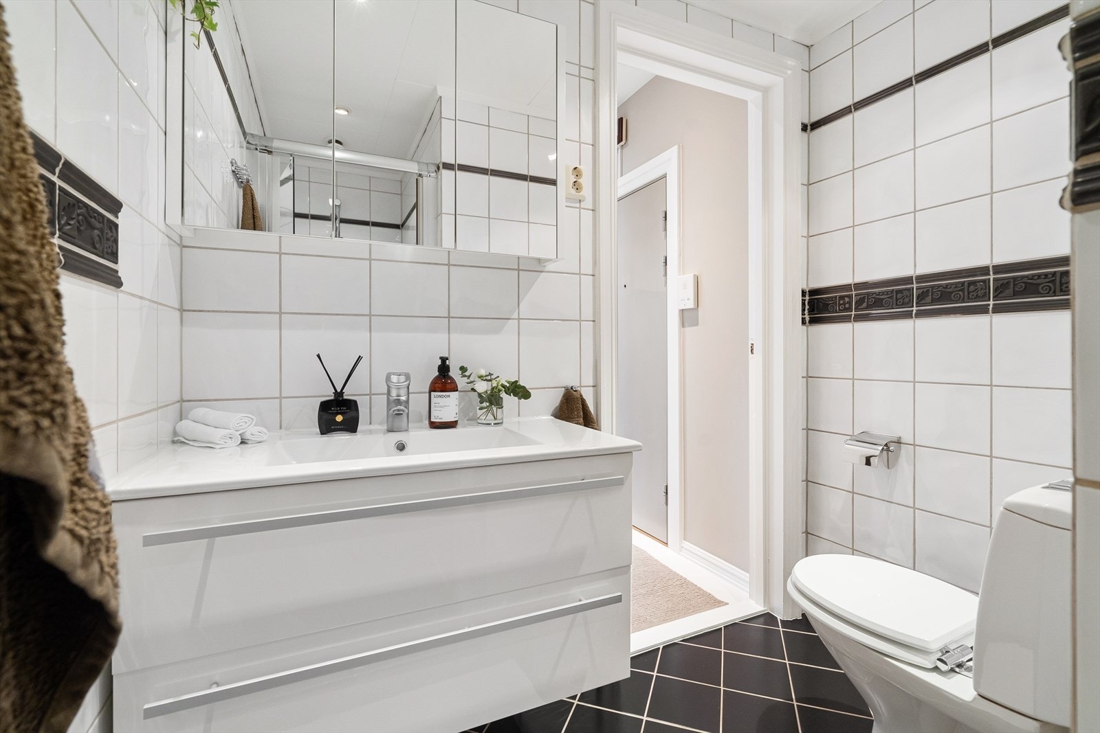 Badet er innredet med klosett, servant nedfelt i innredning, speilskap og dusjhjørne med glassdører. Galleribilde