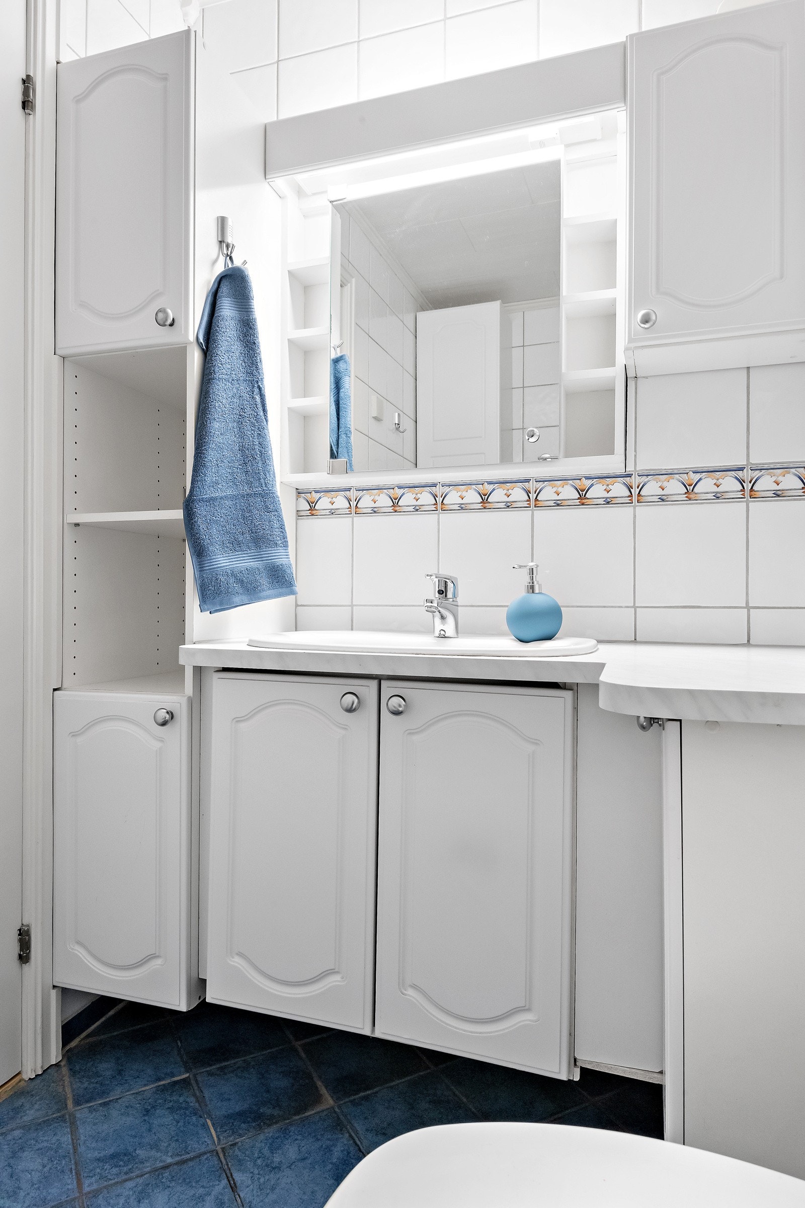 Her har du et praktisk dusjhjørne, opplegg for vaskemaskin, gulvmontert toalett og en klassisk servantinnredning med mye oppbevaringsplass. Galleribilde