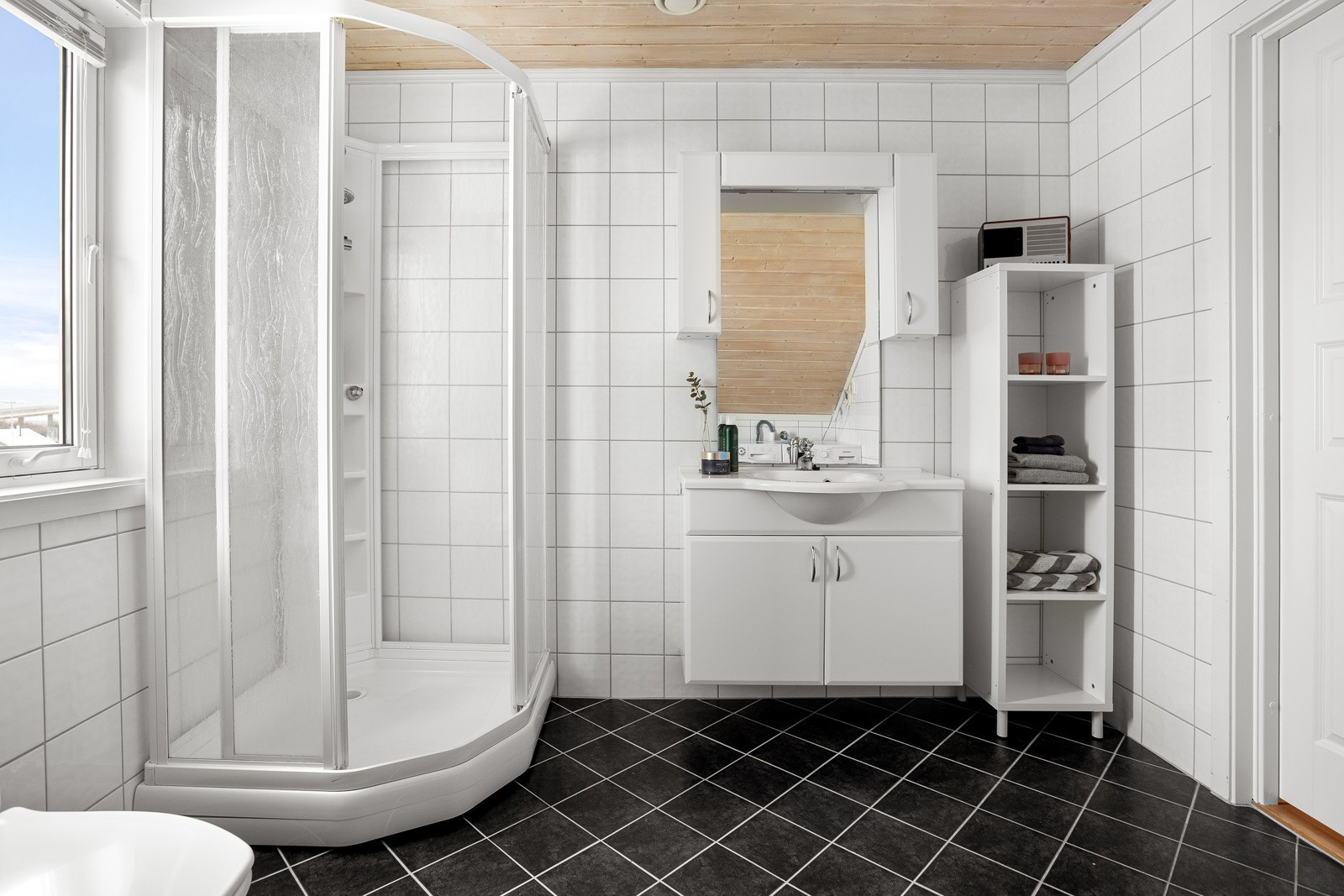 Badet er innredet med dusjkabinett, toalett og servant