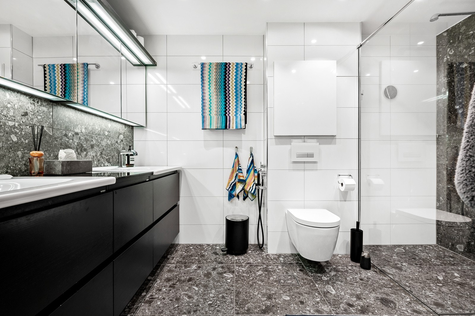 Badet har en svært god størrelse hvor du får dusjhjørne med dobbel regndusj og innfellbar glassdør, vegghengt toalett og veggheng servantskap. Galleribilde