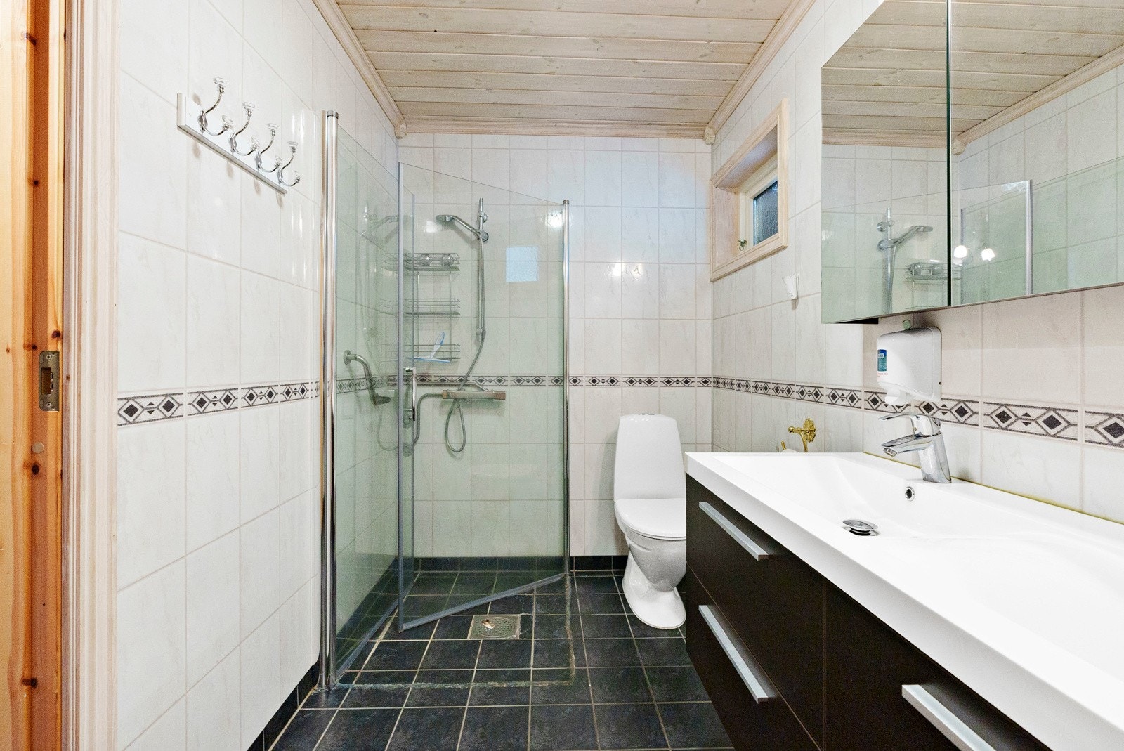 Ett av to bad på hovedplan - dette med flislagt overflater, dusjhjørne, klosett og dobbel servant Galleribilde