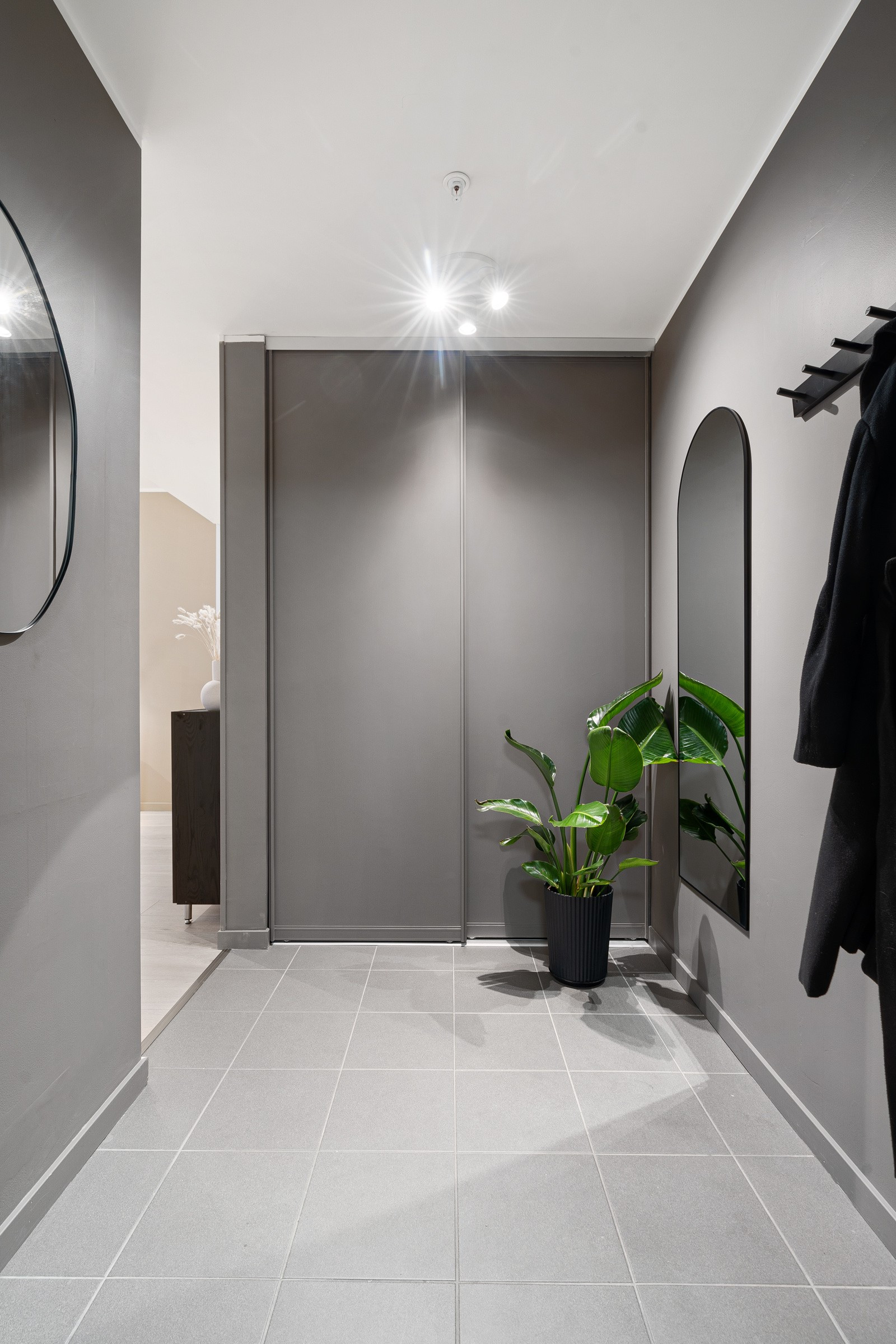 Gangen er malt i en delikat gråfarge og har med oppbevaringsplass i skyvedørsgarderobe.