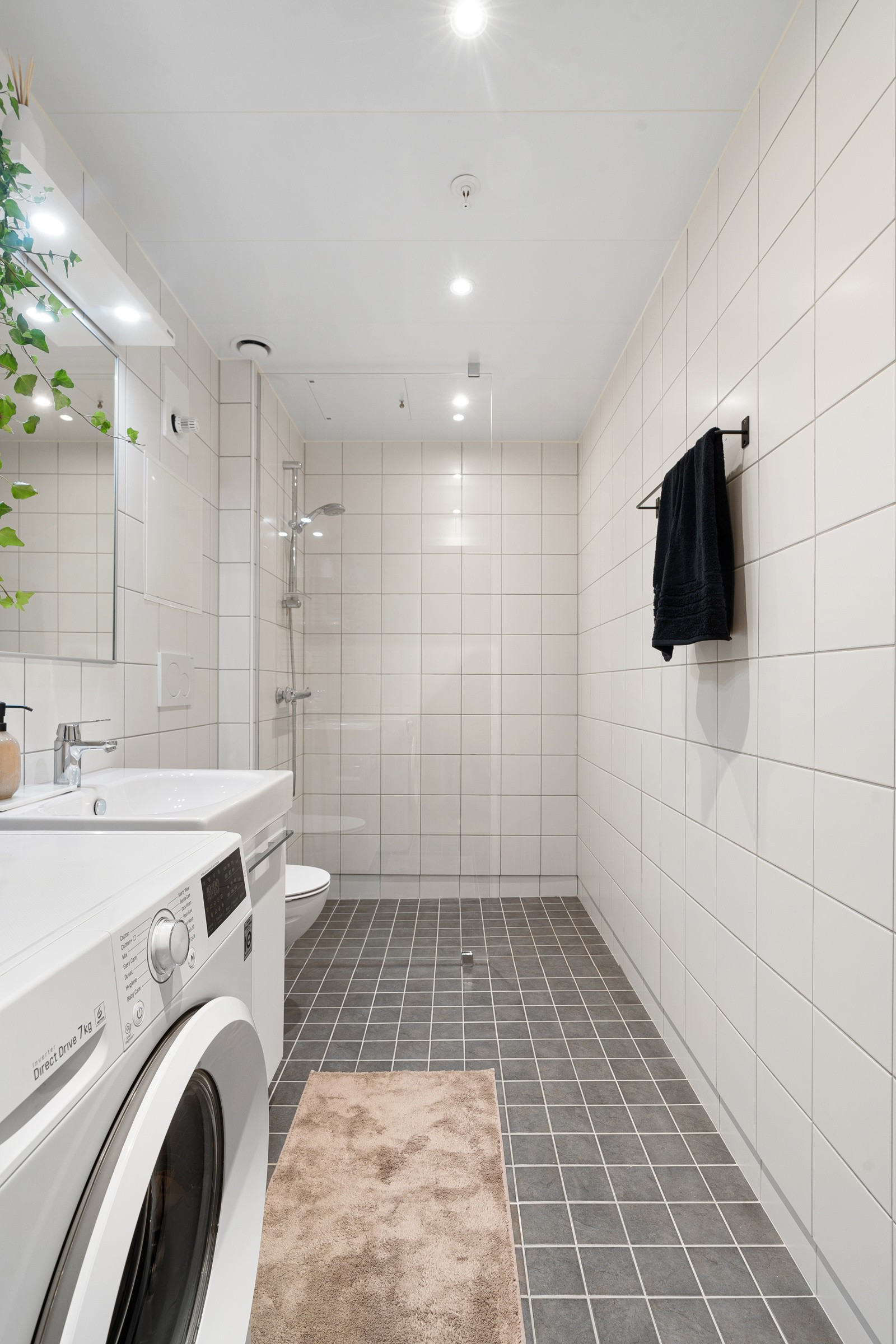 Badet fremstår som romslig med dusjhjørne, vegghengt toalett og moderne baderomsinnredning.