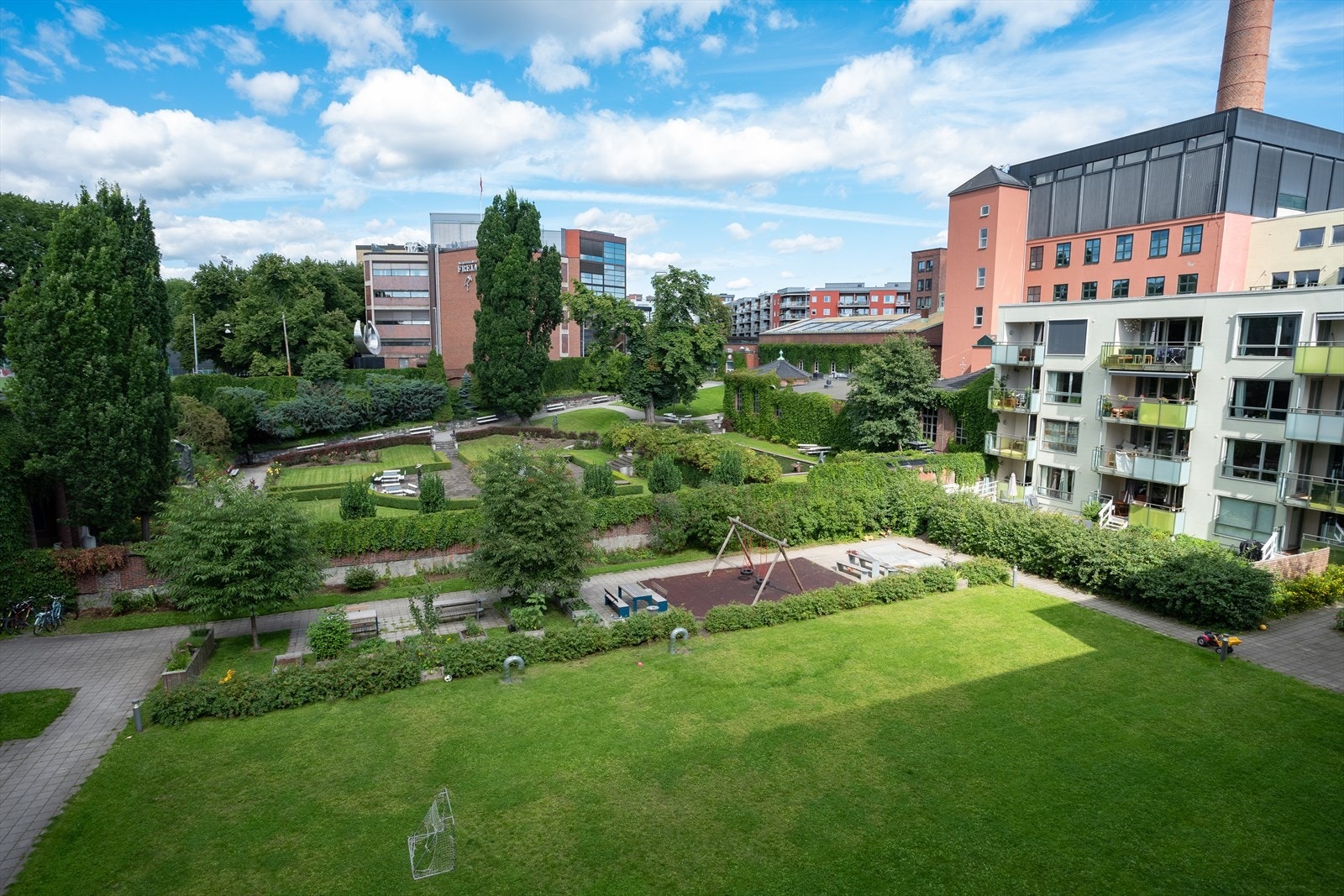 - En stor, skjermet og lukket bakgård med flere sittegrupper, lekestativ og et stort grøntområde - Galleribilde