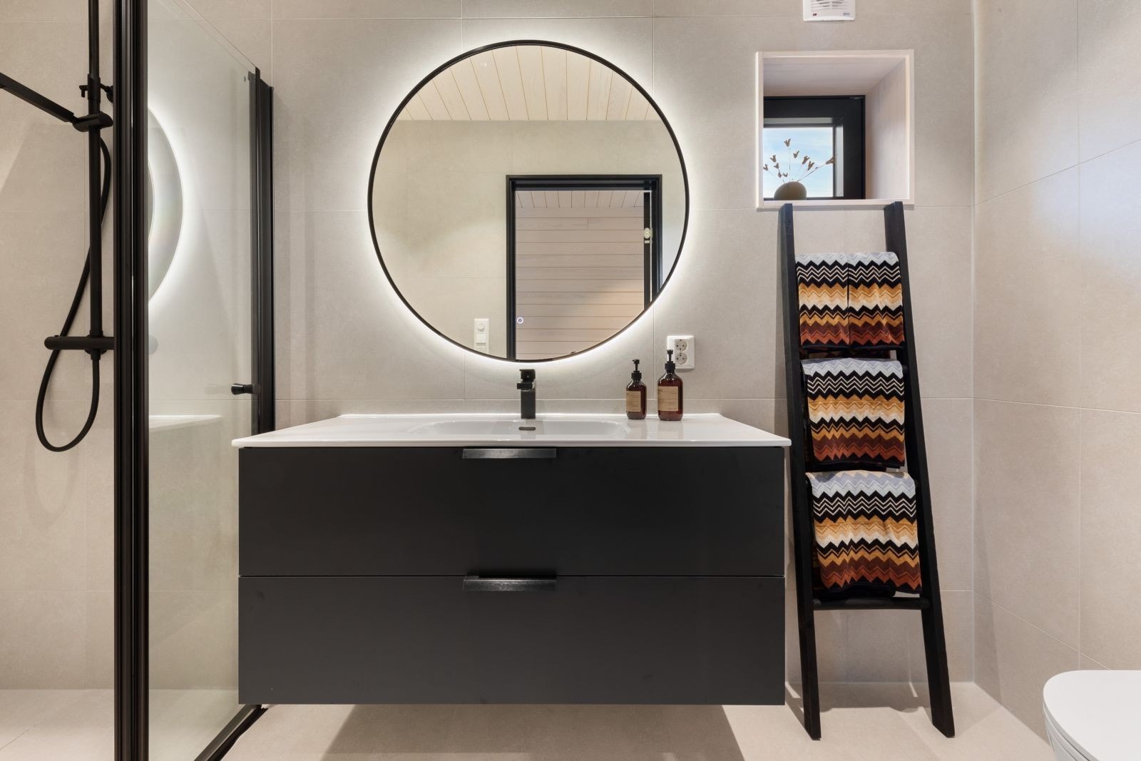 Baderom som består av servant over innredning, speil, dusj og vegghengt toalett Galleribilde