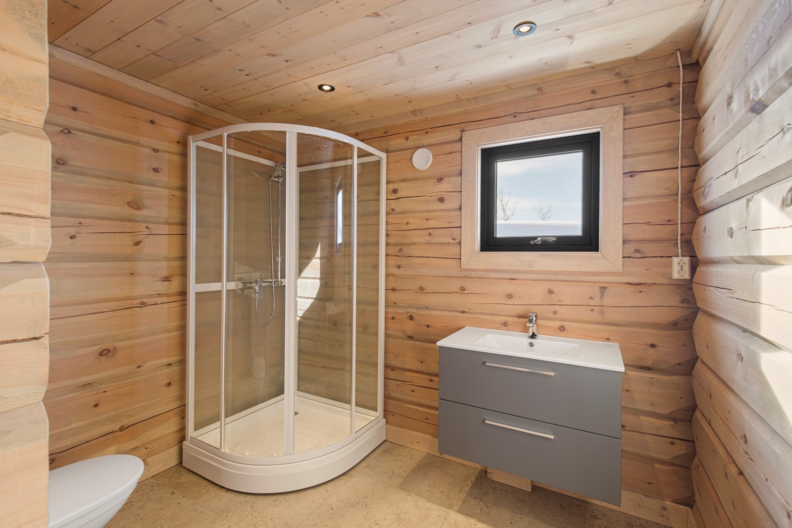 Badet har samme tidløse 60x60-flis som hall og vaskerom, og det er montert veggholdt toalett, gulvvarme, dusjkabinett og baderomsinnredning Galleribilde