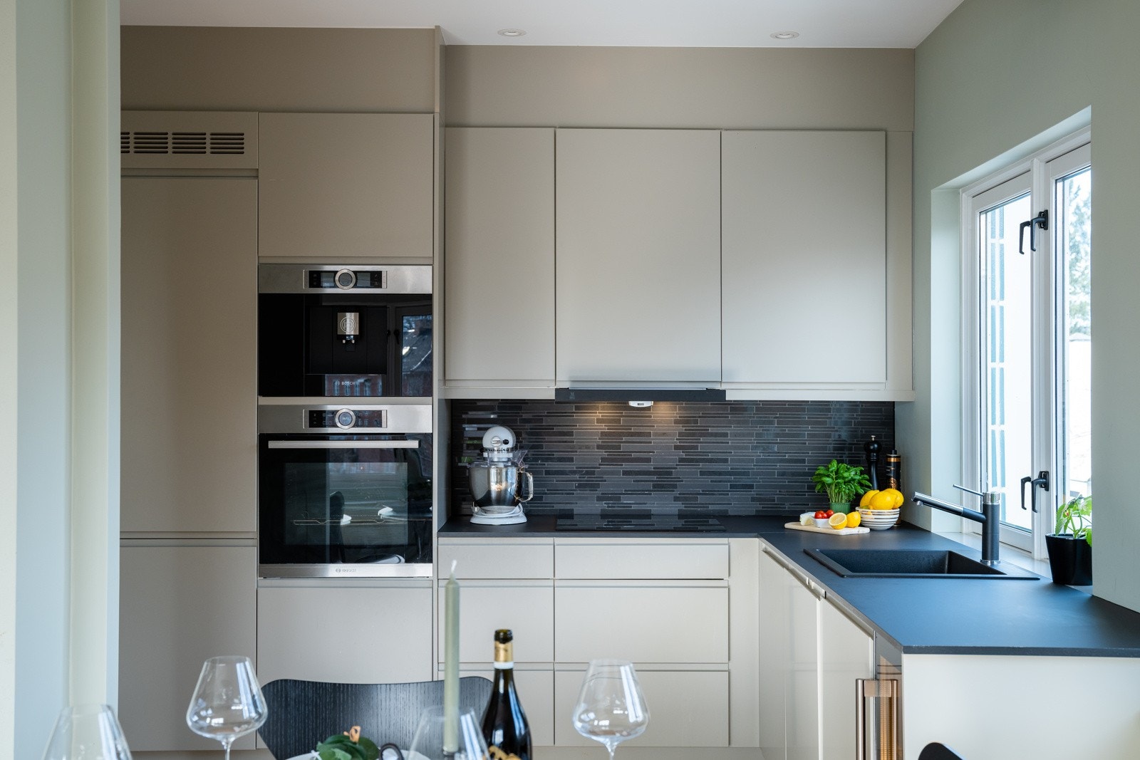 Stilren og moderne kjøkkeninnredning fra 2019 med slette, håndtaksløse fronter og flislagt backsplash. Galleribilde
