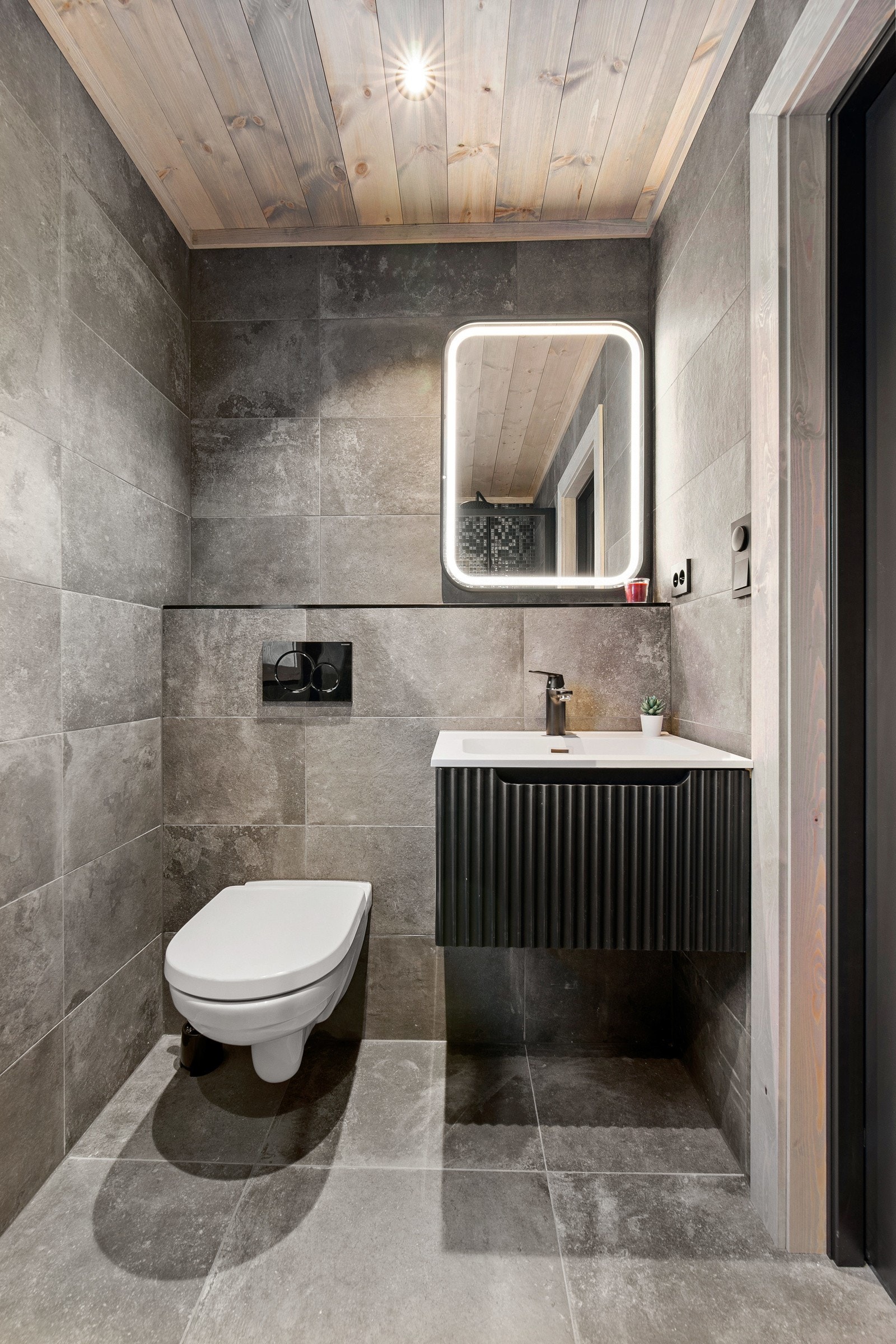 Flott flislagt bad med vegghengt toalett og servant Galleribilde