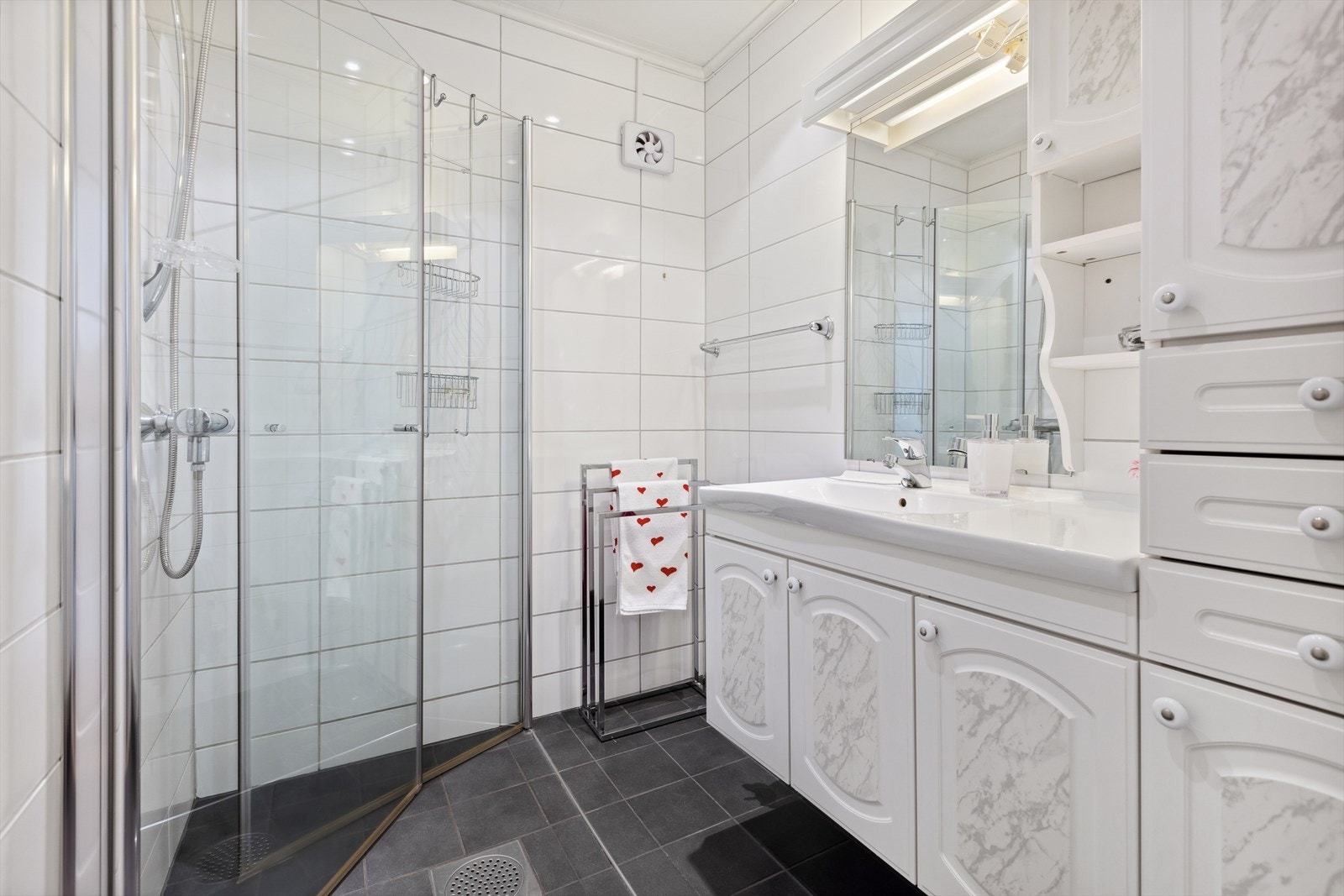 På badet er det dusjhjørne m/glassdører og dusjgarnityr, baderomsinnredning m/heldekkende servant, speil og lys. God skapplass. Galleribilde