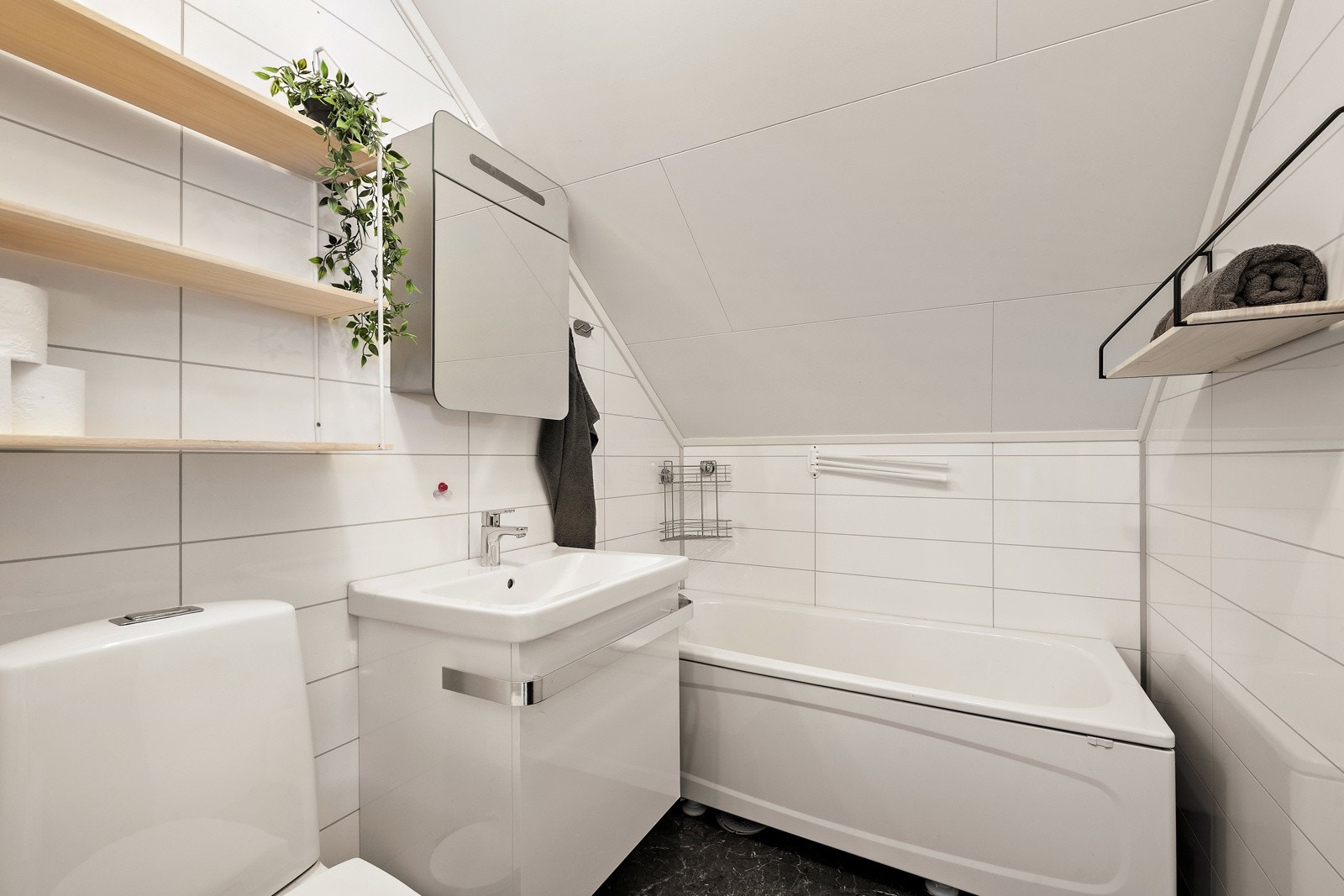 Baderommet ble pusset opp i 2015 med nøytrale og tidløse fargevalg. Innmontert servant, gulvmontert toalett og badekar med veggmontert blandebatteri. Galleribilde