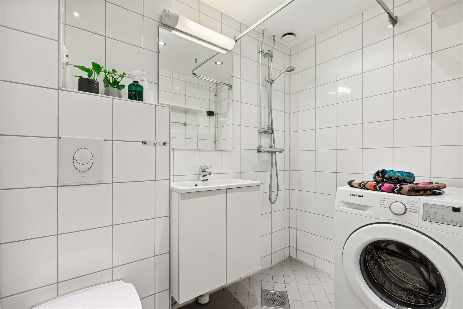 Innredningen består av heldekkende servant på benkeseksjon med hvite, glatte skapfronter, speil med overlys samt veggmontert toalett. Det er opplegg for vaskemaskin på badet Galleribilde