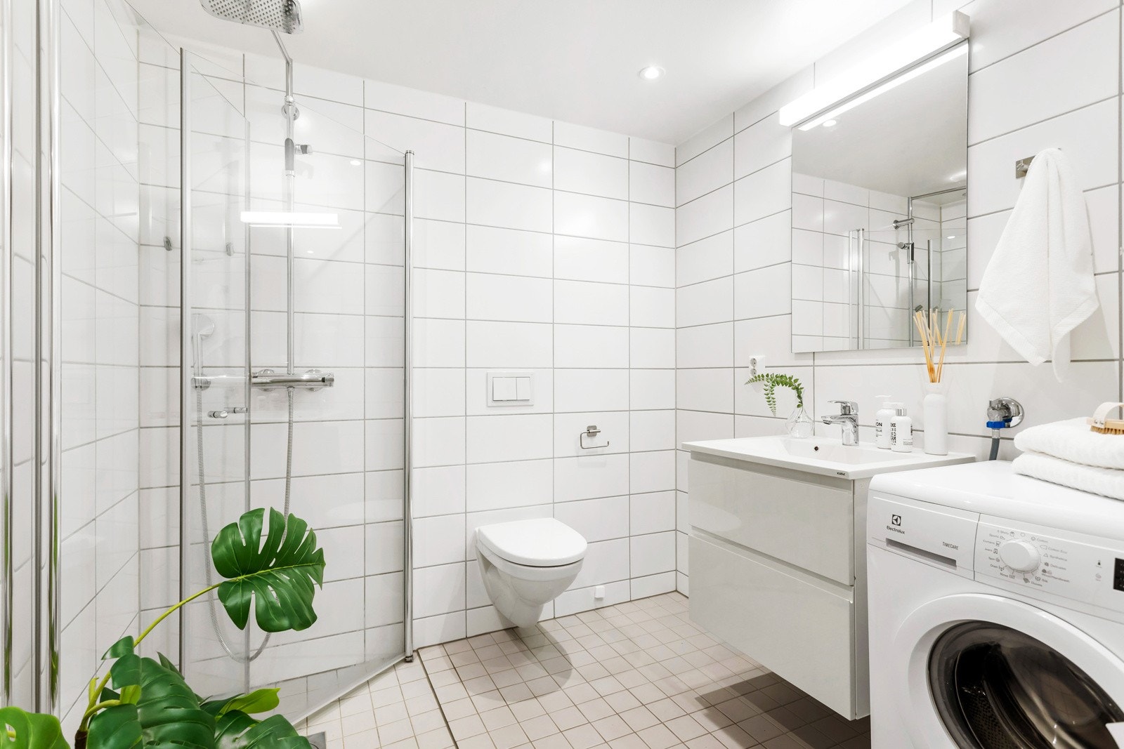 Boligen har et lyst og pent bad med flislagte overflater, gulvvarme og downlights i himling Galleribilde