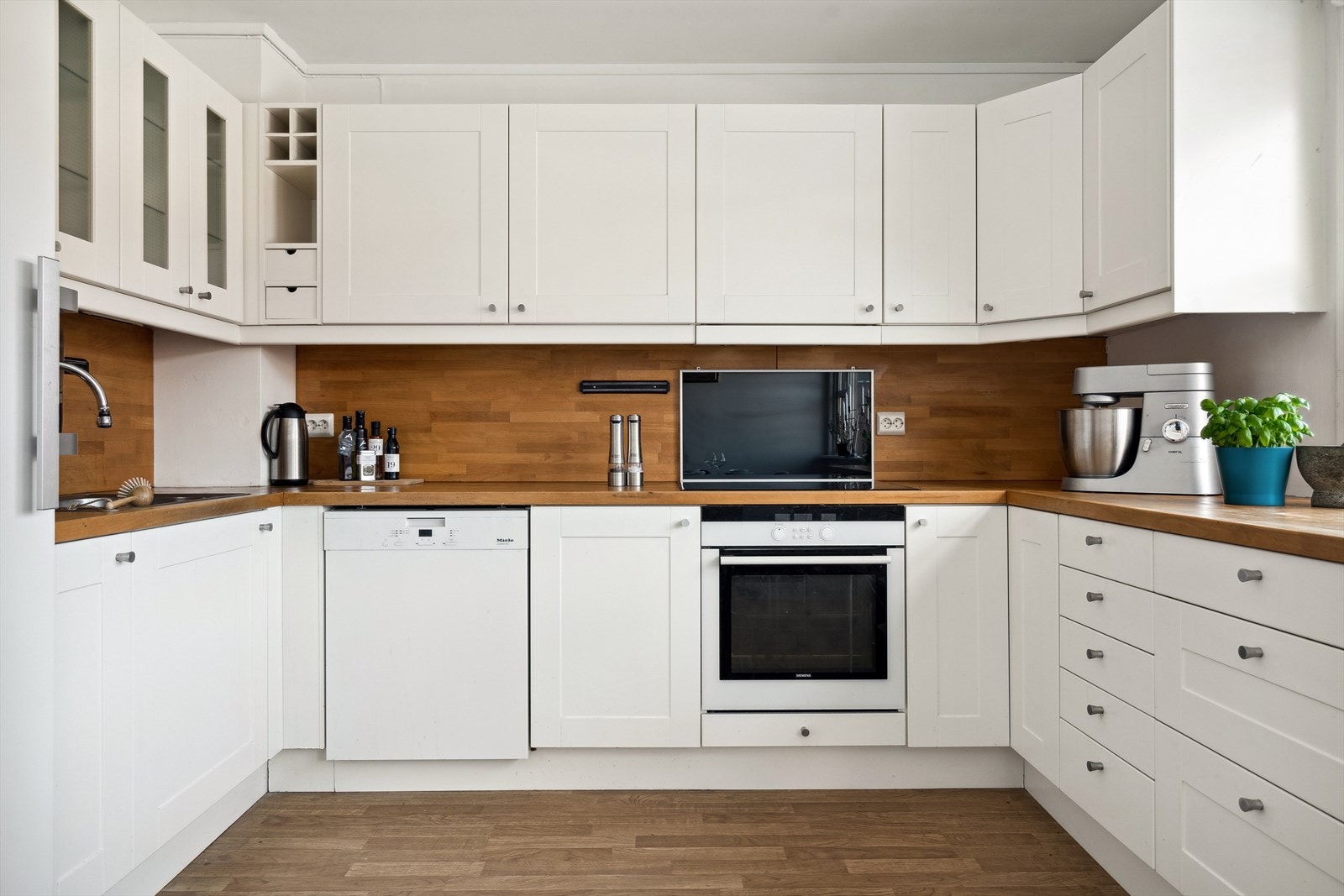 Integrert oppvaskmaskin, oppvaskkum, stekeovn, induksjonstopp og frittstående kjøleskap. Galleribilde