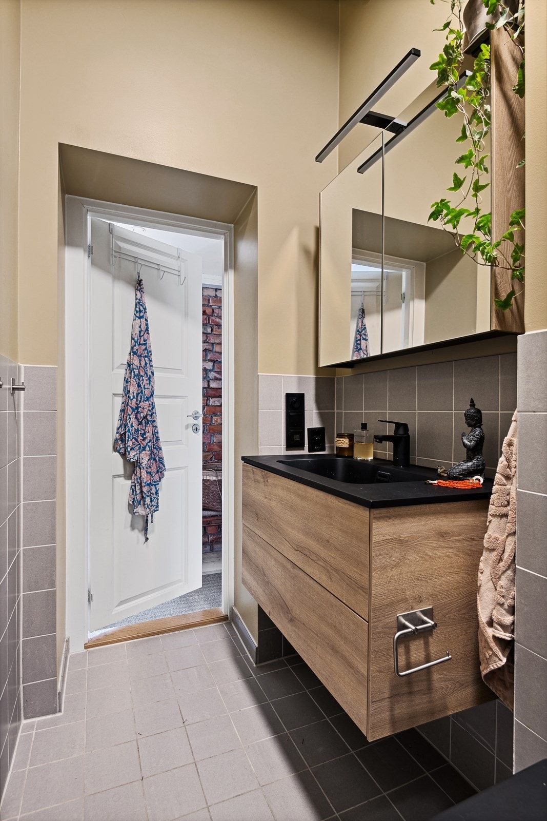 Badet består av vegghengt wc, servant med underskap, overskap med speilfronter og overlys, samt åpen dusj med glassvegg mot innredning Galleribilde
