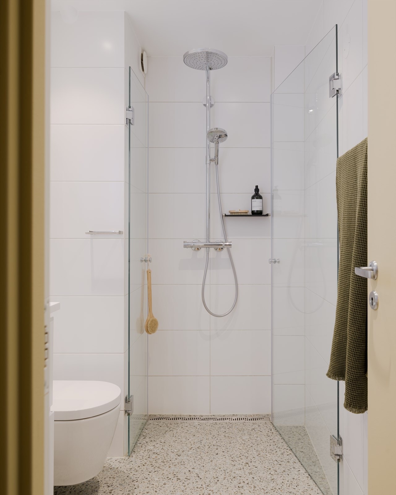 Moderne Terrazzofliser på gulv er lekkert kombinert med klassiske store fliser på vegg. Veggmonterte svingbare dusjvegger. Galleribilde