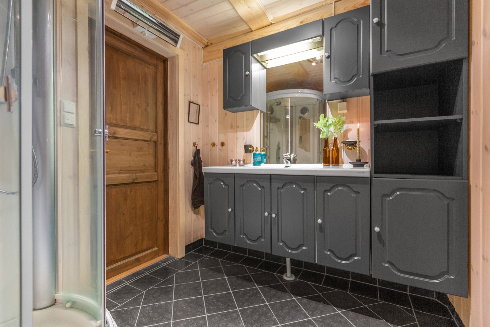 Baderomsinnredning med god oppbevaringsplass. Badet er videre innredet med dusjkabinett og gulvmontert wc. Galleribilde