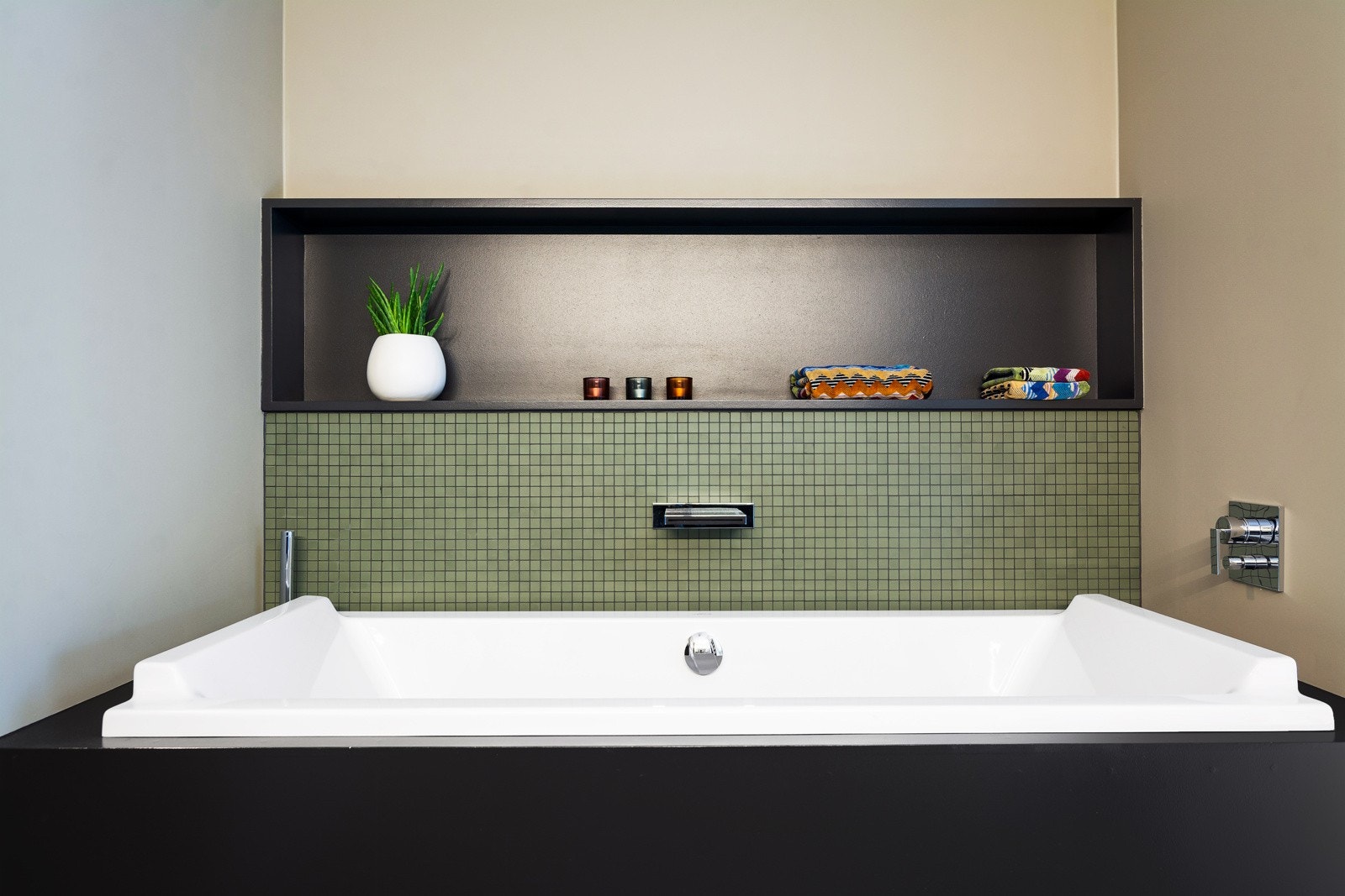 Innebygget badekar med integrert dusjløsning, armatur med fossefall og bred hylle over karet. Galleribilde