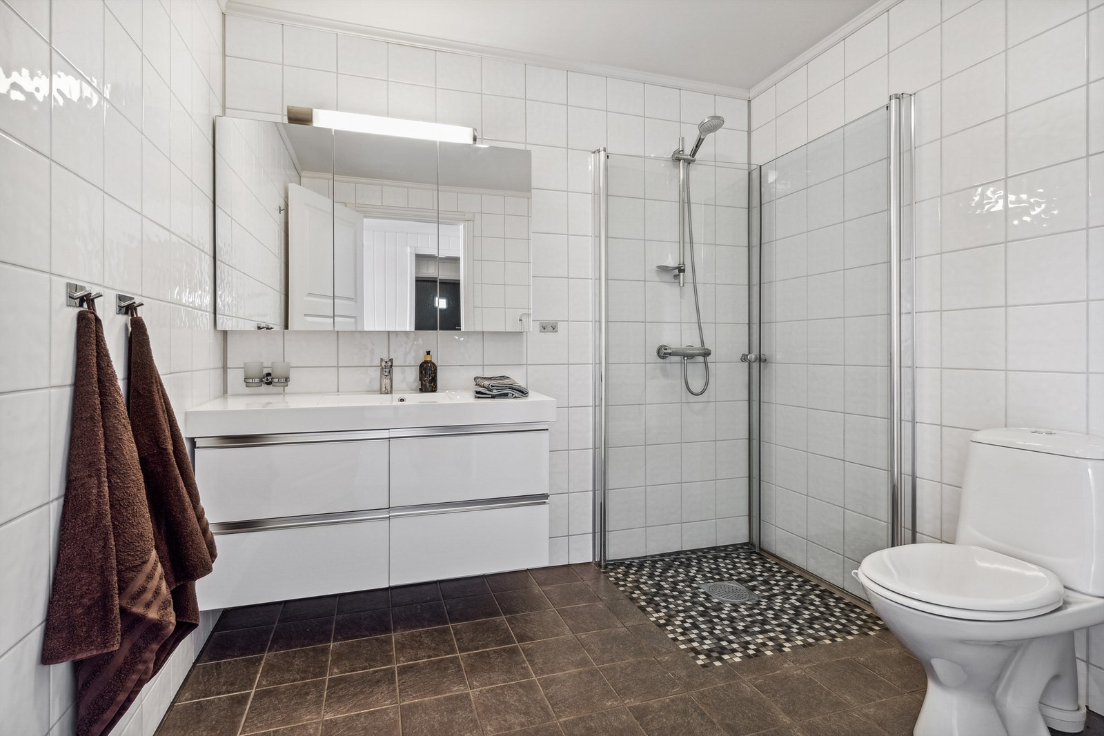 Flislagt bad, installert med baderomsinnredning, gulvmontert WC, dusjnisje. Galleribilde