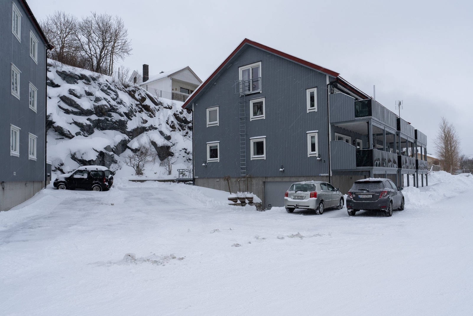 Fasade mot nord med gjesteparkering og port mot parkeringsgarasje. Galleribilde