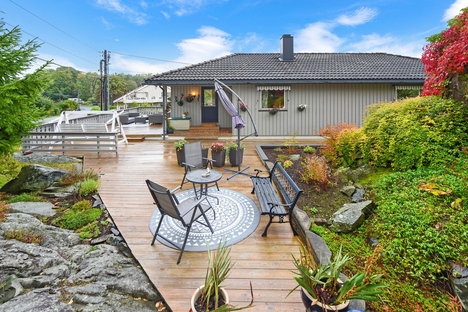 Ut fra stuen, bak huset er det utgang til stor terrasse som går rundt store deler av boligen og videre over terreng. Galleribilde