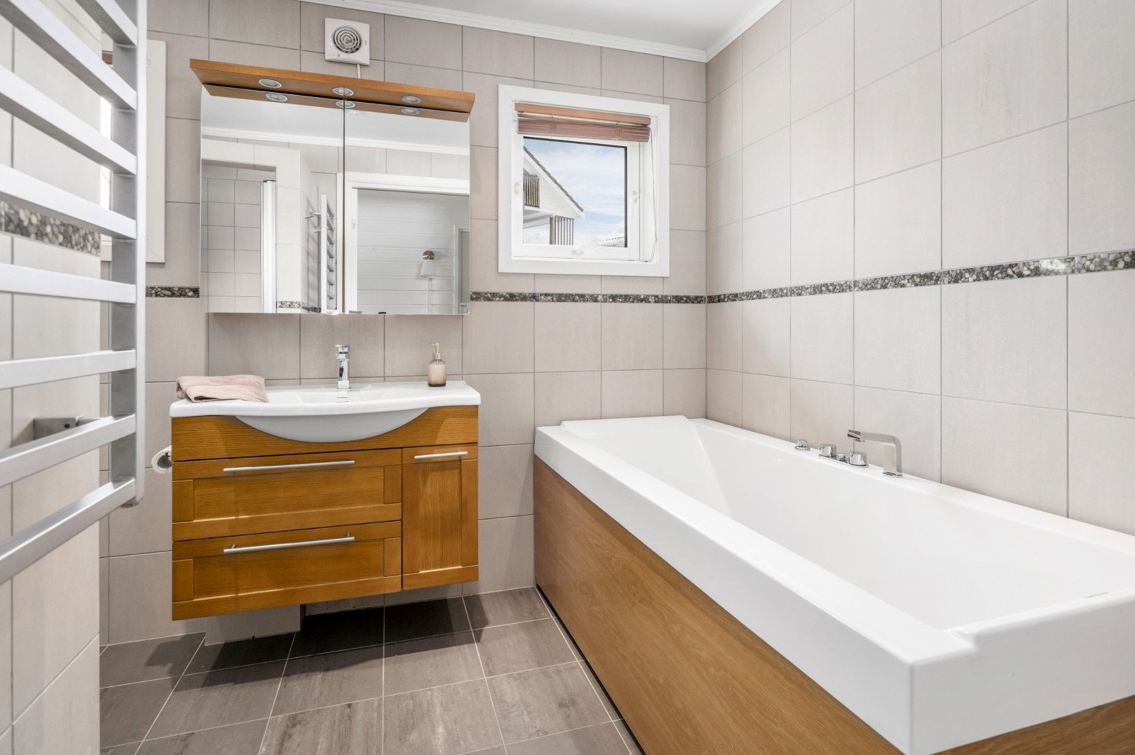 Badet er utstyrt med dusjnisje, veggmontert wc, servantskap, badekar og mekanisk avtrekk. Galleribilde
