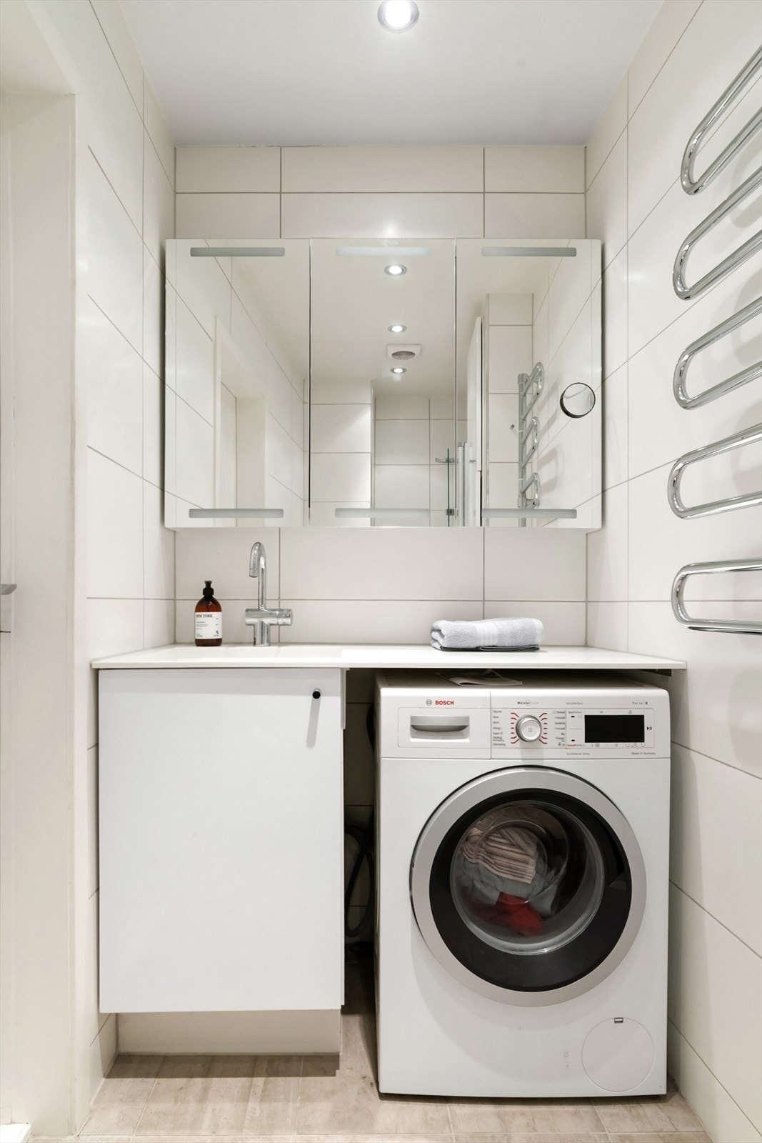 Badet består av blant annet overskap med speil, håndklevarmer, servant med underskap og egen nisje med plass til vaskemaskin Galleribilde