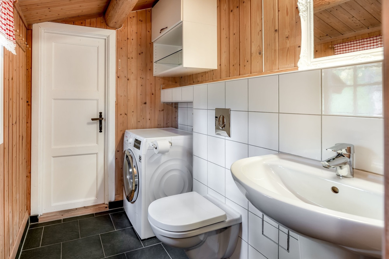 Baderom med varmekabler og flislagt gulv. Panel/flislagte vegger. Vegghengt toalett fra 2021, servant, dusjhjørne, varmvannsbereder og avsatt plass til vaskemaaskin Galleribilde