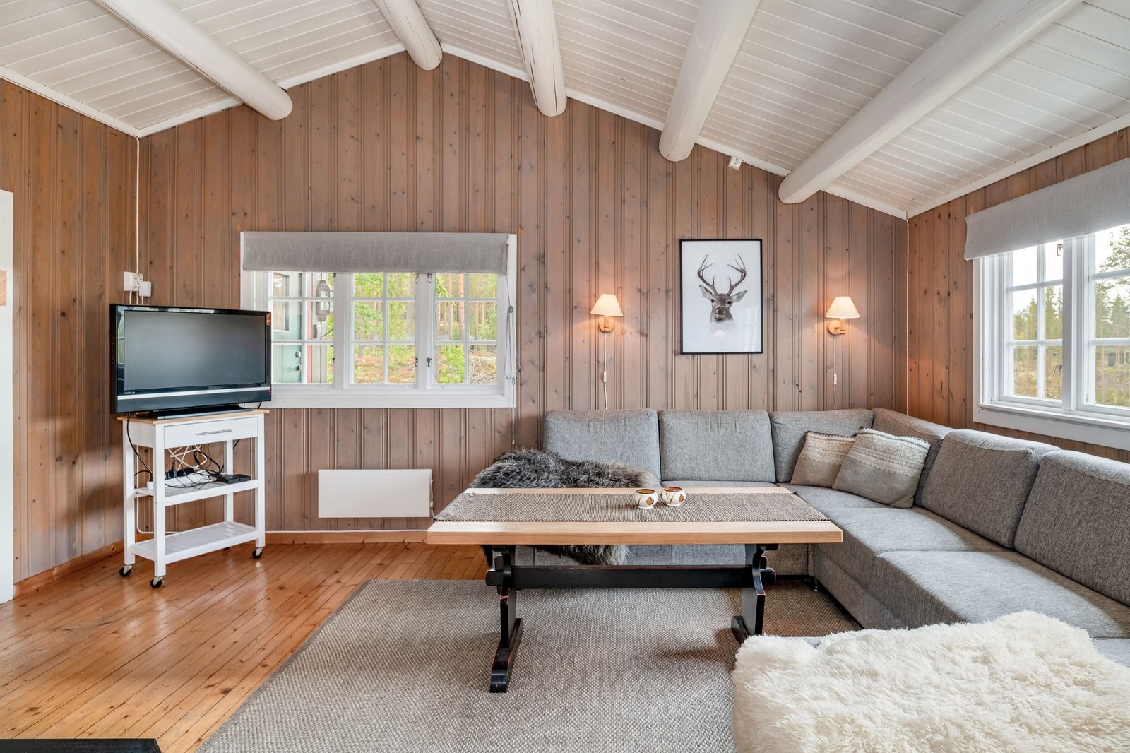 Stue med fin takhøyde, tregulv, malt tretak med synlige åser og malt veggpanel Galleribilde