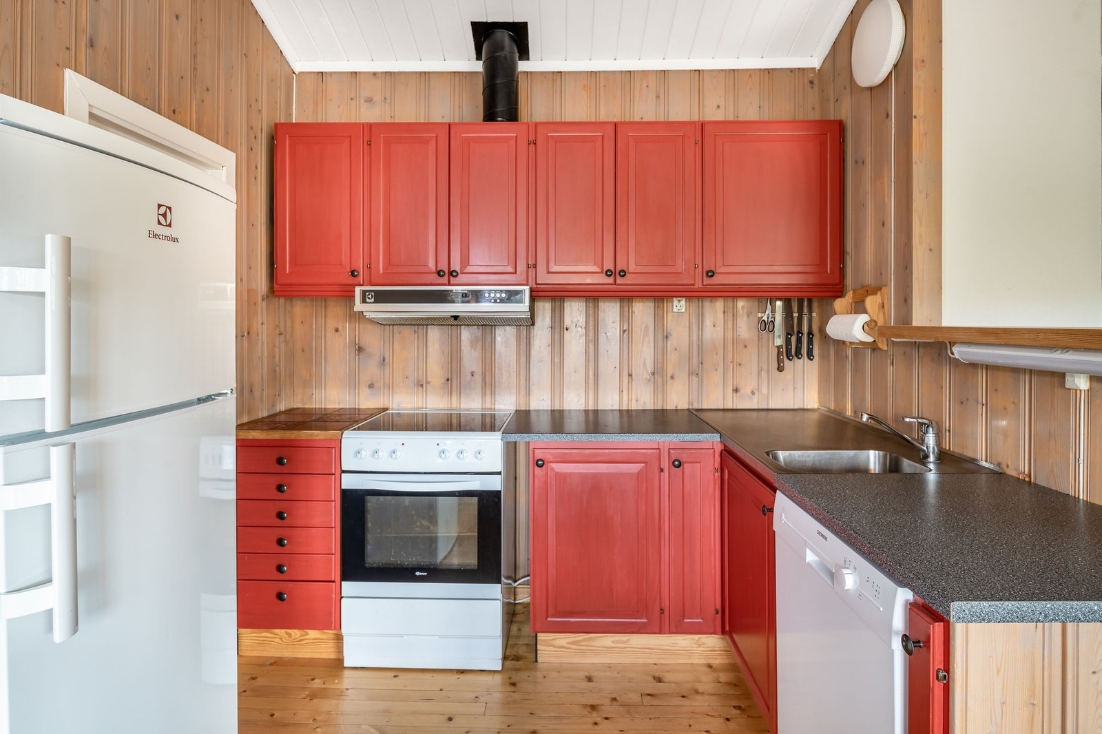 Kjøkkeninnredning med heltre malte fyllingsfronter, ventilator, integrert oppvaskmaskin og avsatt plass til komfyr og kjøleskap Galleribilde