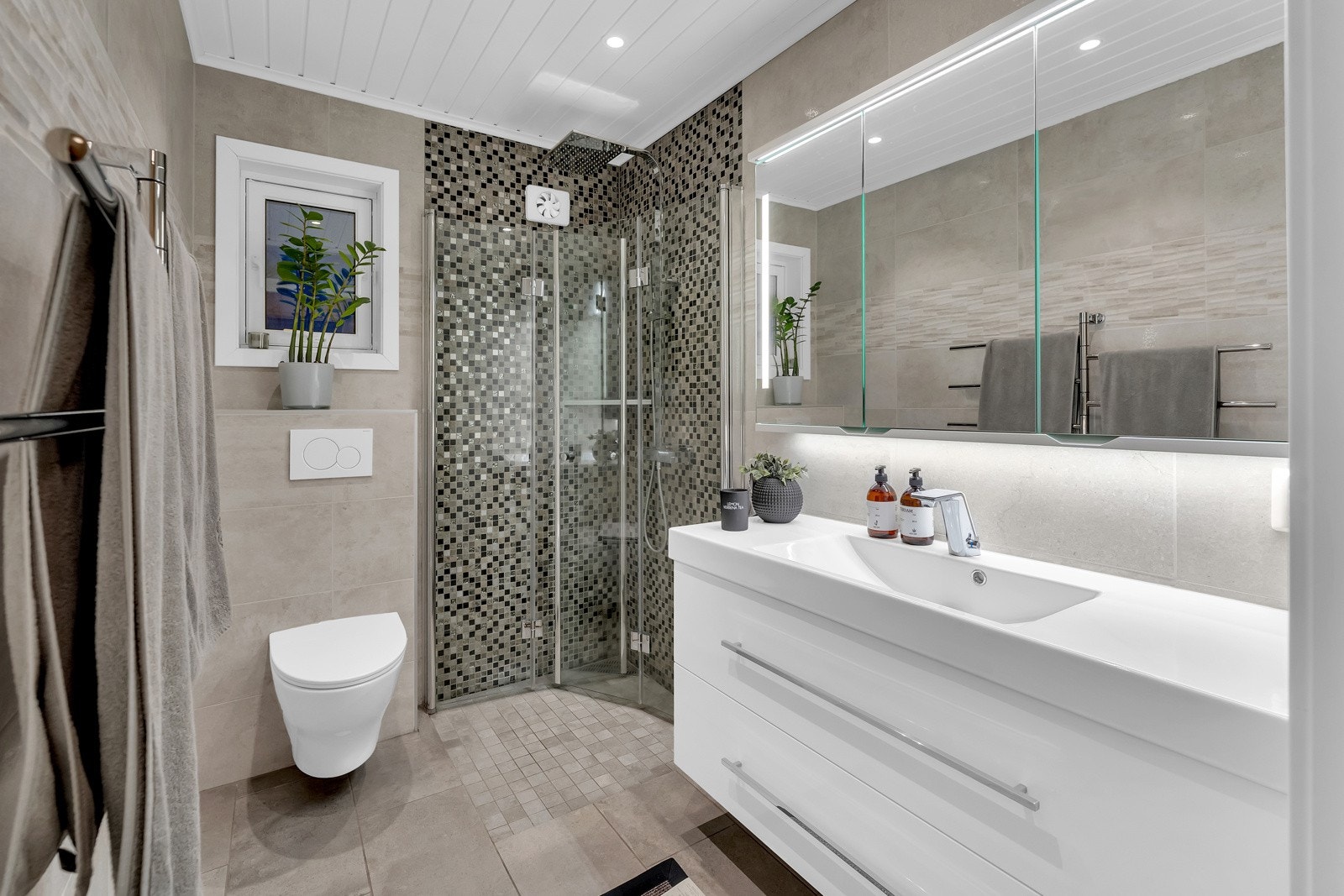 Badet i 1.etasje ble pusset opp i 2018 og fremstår nytt og mordene. Baderomsinnredningen består av benkeskap, veggskap med speilfronter og belysning over servant. Badet har dusj, servant og veggfestet toalett. Galleribilde