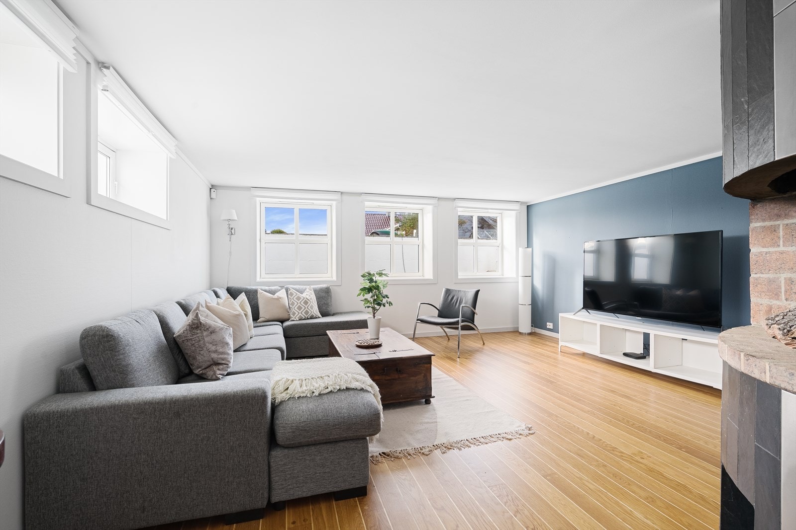 Stor og luftig stue med parkett på gulv, tidsriktig kontastvegg og mye naturlig daglys. God plass til sittegruppe og TV-seksjon. Galleribilde