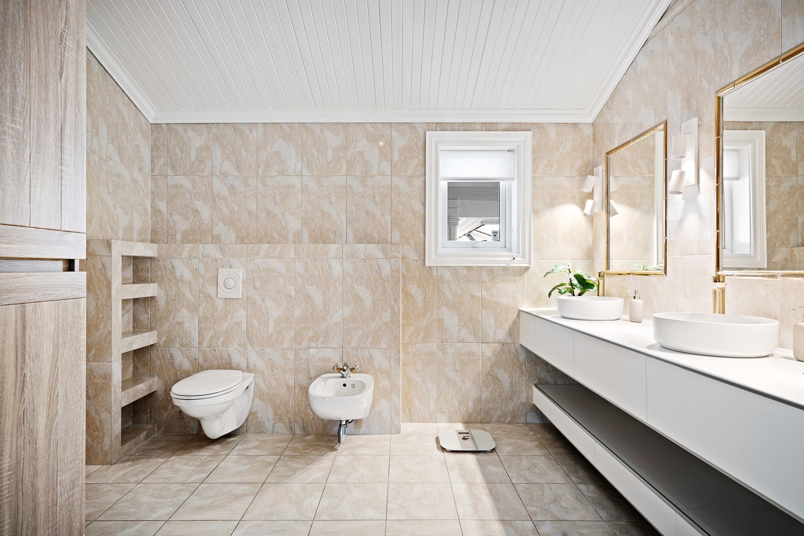 Lekkert helfliset bad med moderne innredning, plassbygget hyller, dobbel servant med trendy messingfargede amaturer, vegghengt toalett, bidé og dusjnisje. Galleribilde