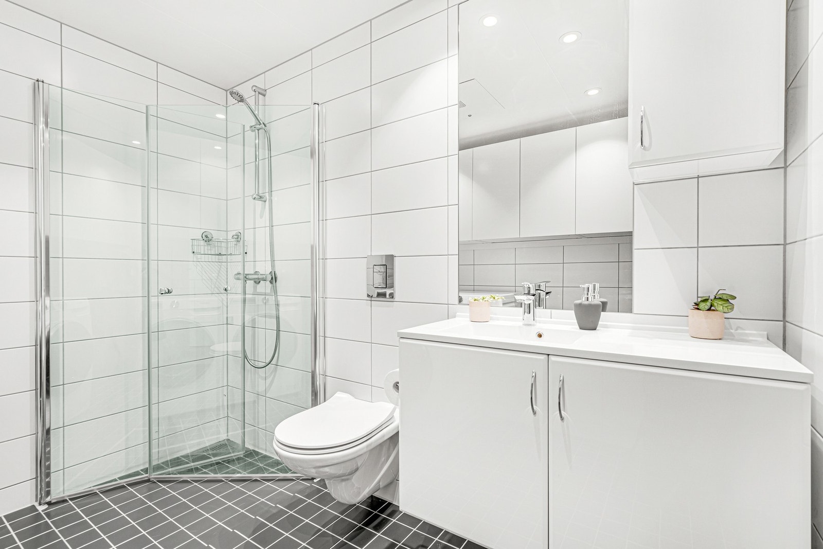 Dusjhjørne med innfellbare glassvegger, vegghengt WC og baderomsinnredning. Galleribilde