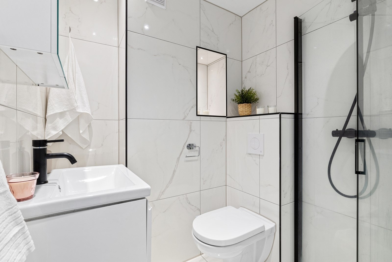 Baderommet er innredet med dusj, servant med underskap, speil med lys, veggmontert toalett, samt opplegg for vaskemaskin. Galleribilde