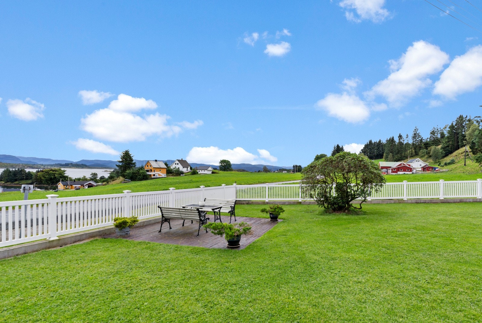 Flott opparbeida hage med plen, beplatning, stakittgjerde og flere fine uteplasser Galleribilde