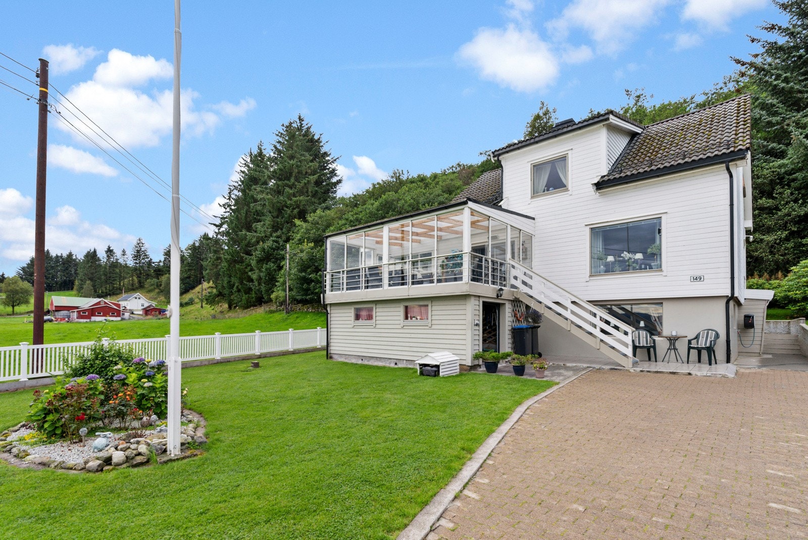 Tomta ved bolighuset har en flott opparbeida hage med grøntarealer, tunplass med belegningsstein og veranda Galleribilde